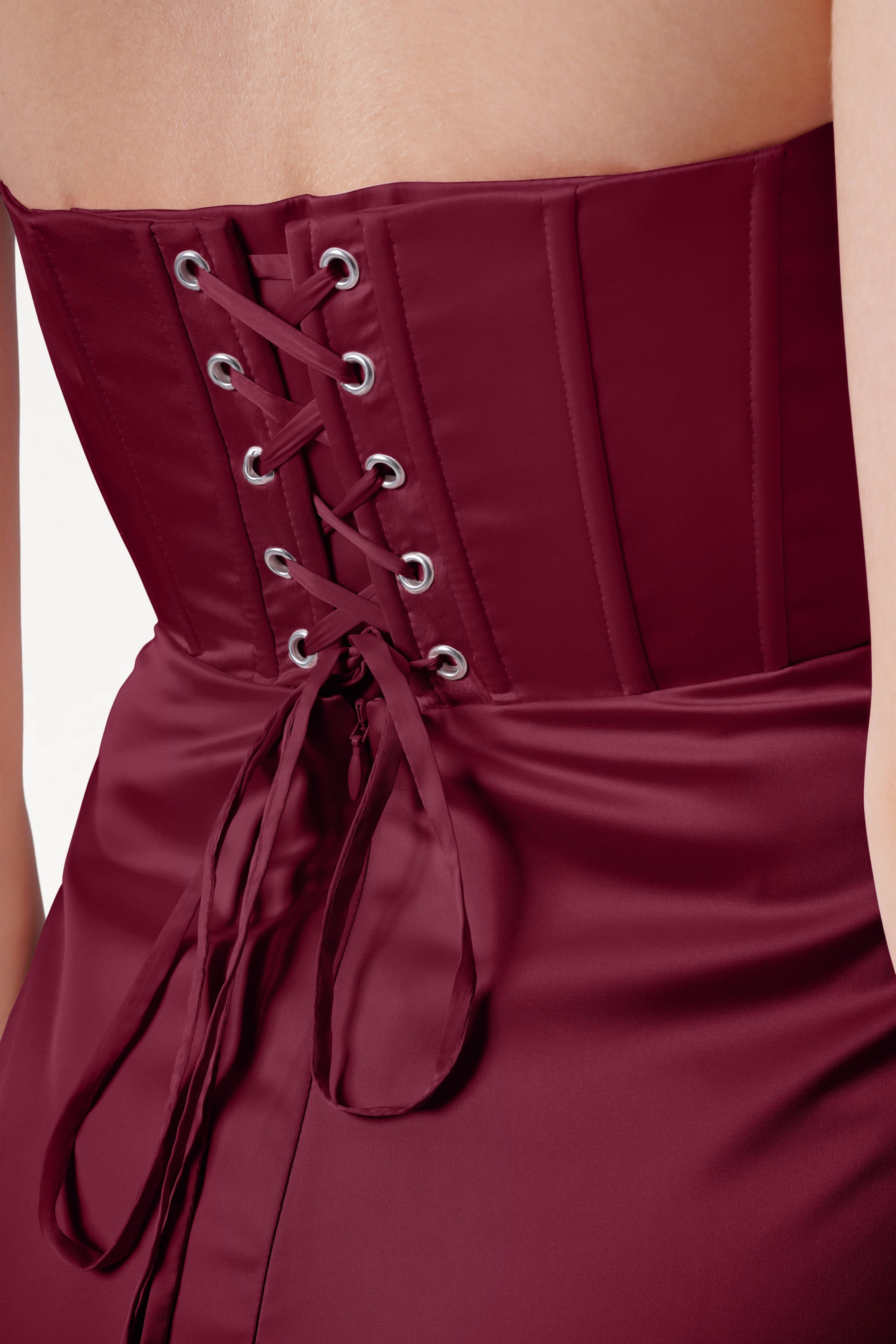 Close-up of a burgundy strapless dress with lace-up front on a neutral background