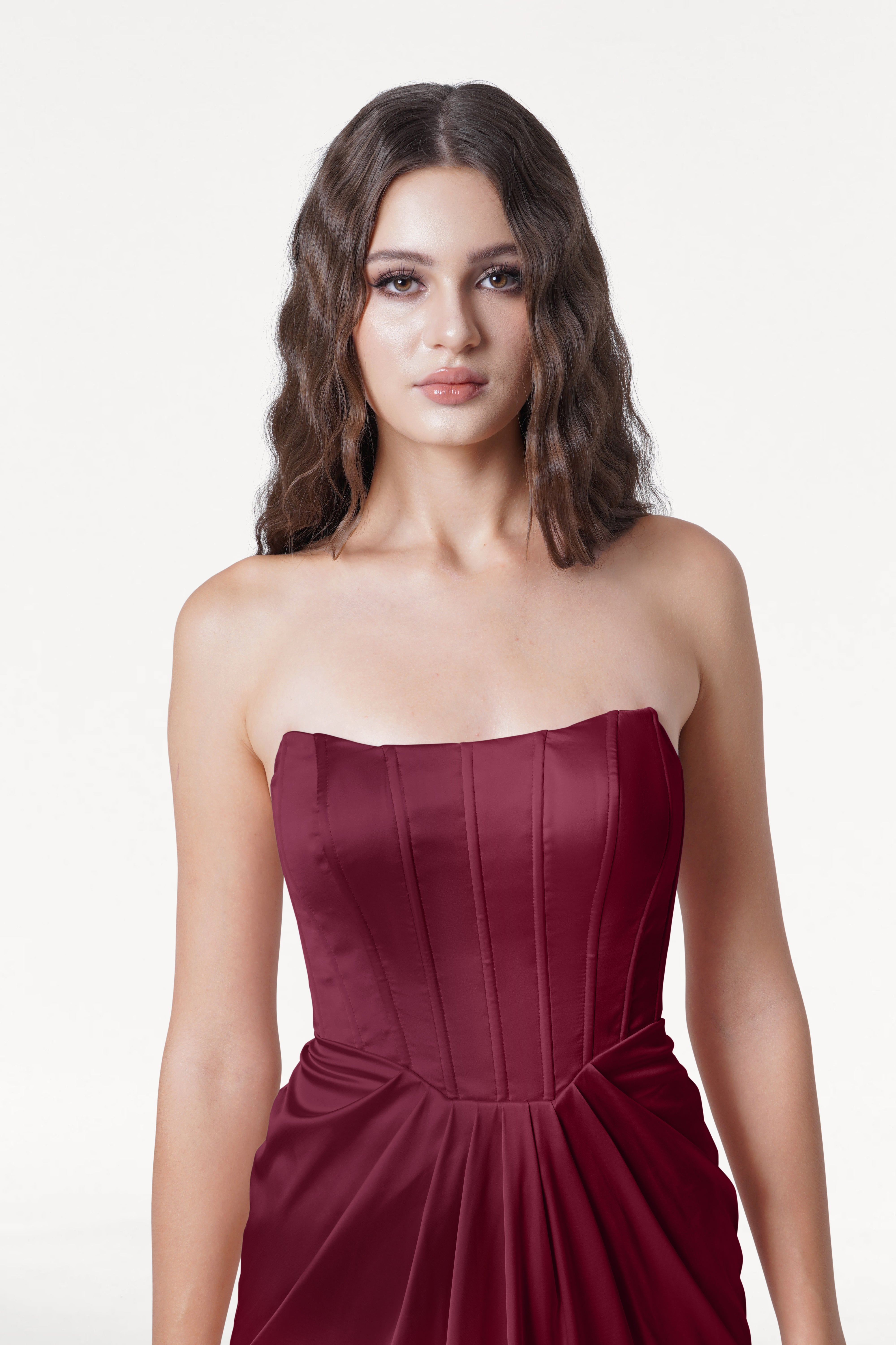 Woman wearing a strapless burgundy dress on a white background
