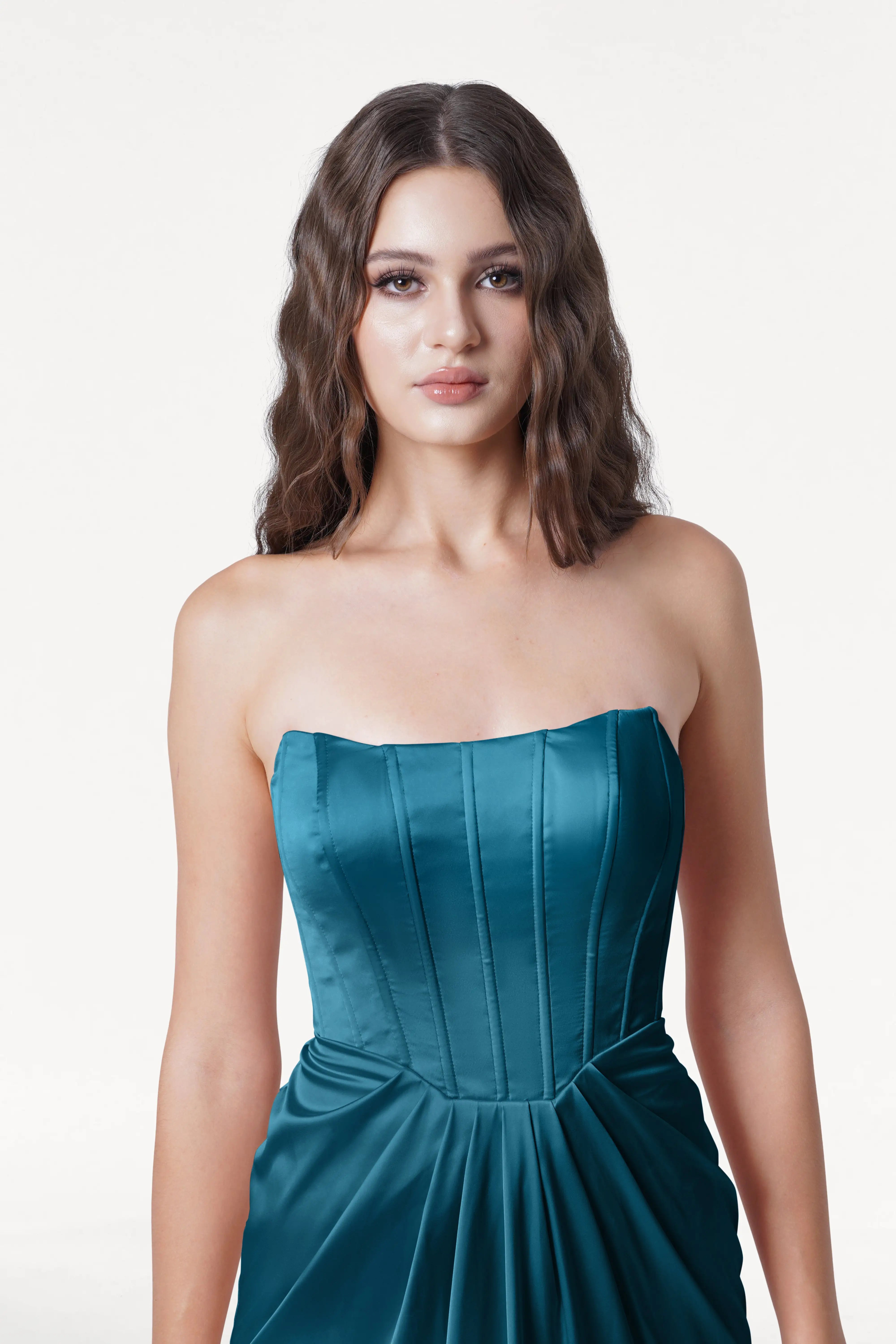 Woman wearing a strapless teal dress on a white background