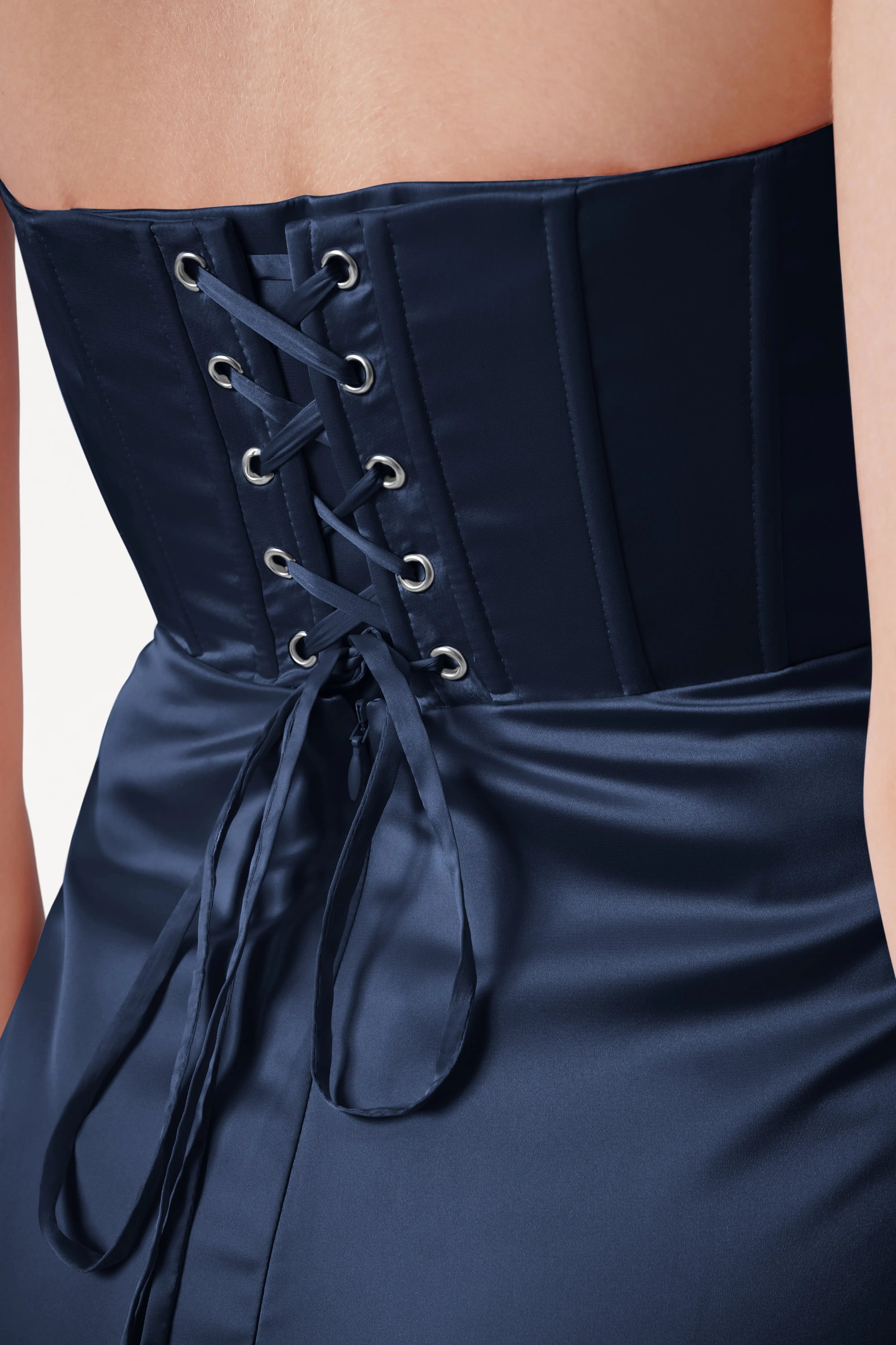 Navy corset dress with lace-up back on a neutral background