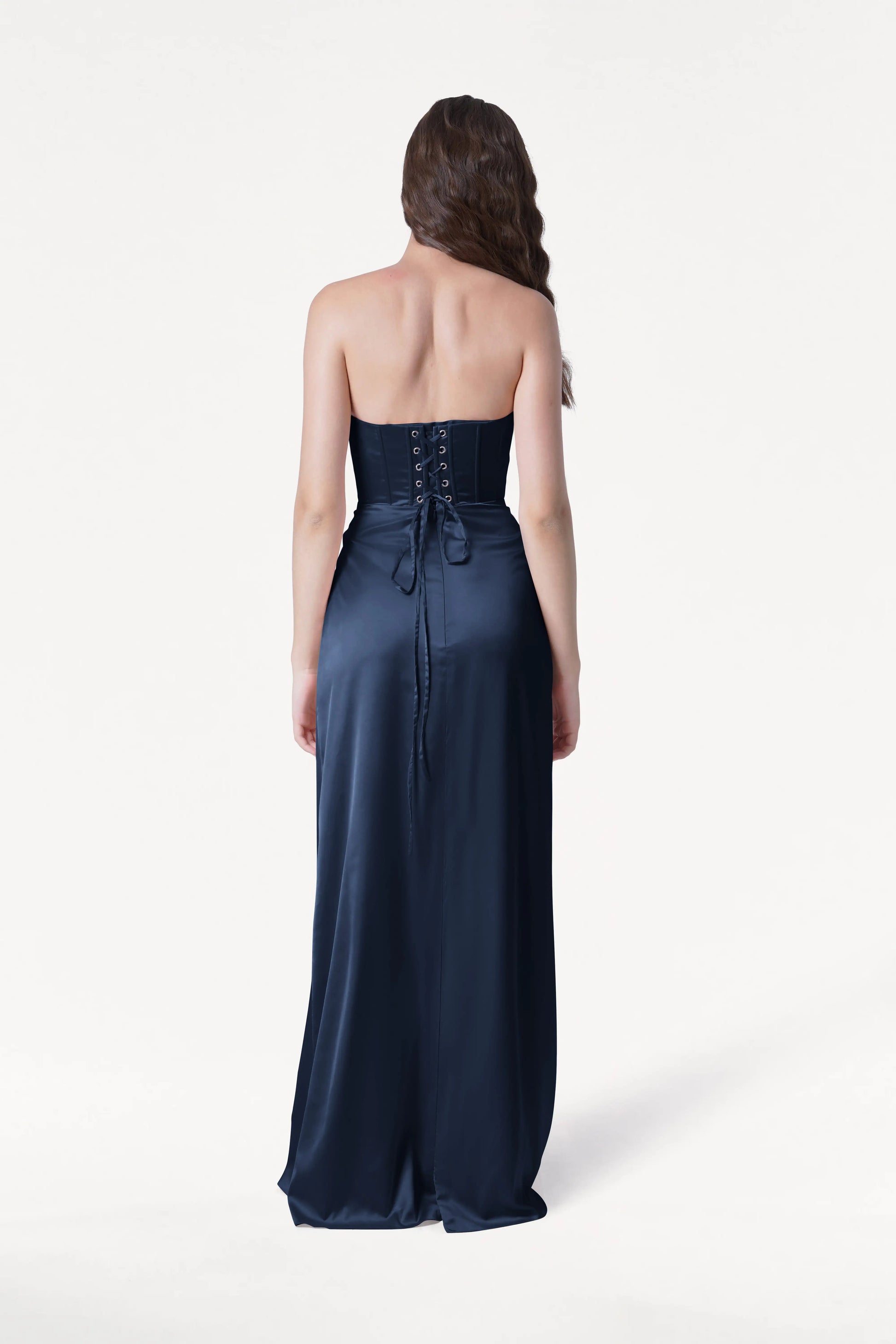 Woman wearing a strapless navy gown on a white background