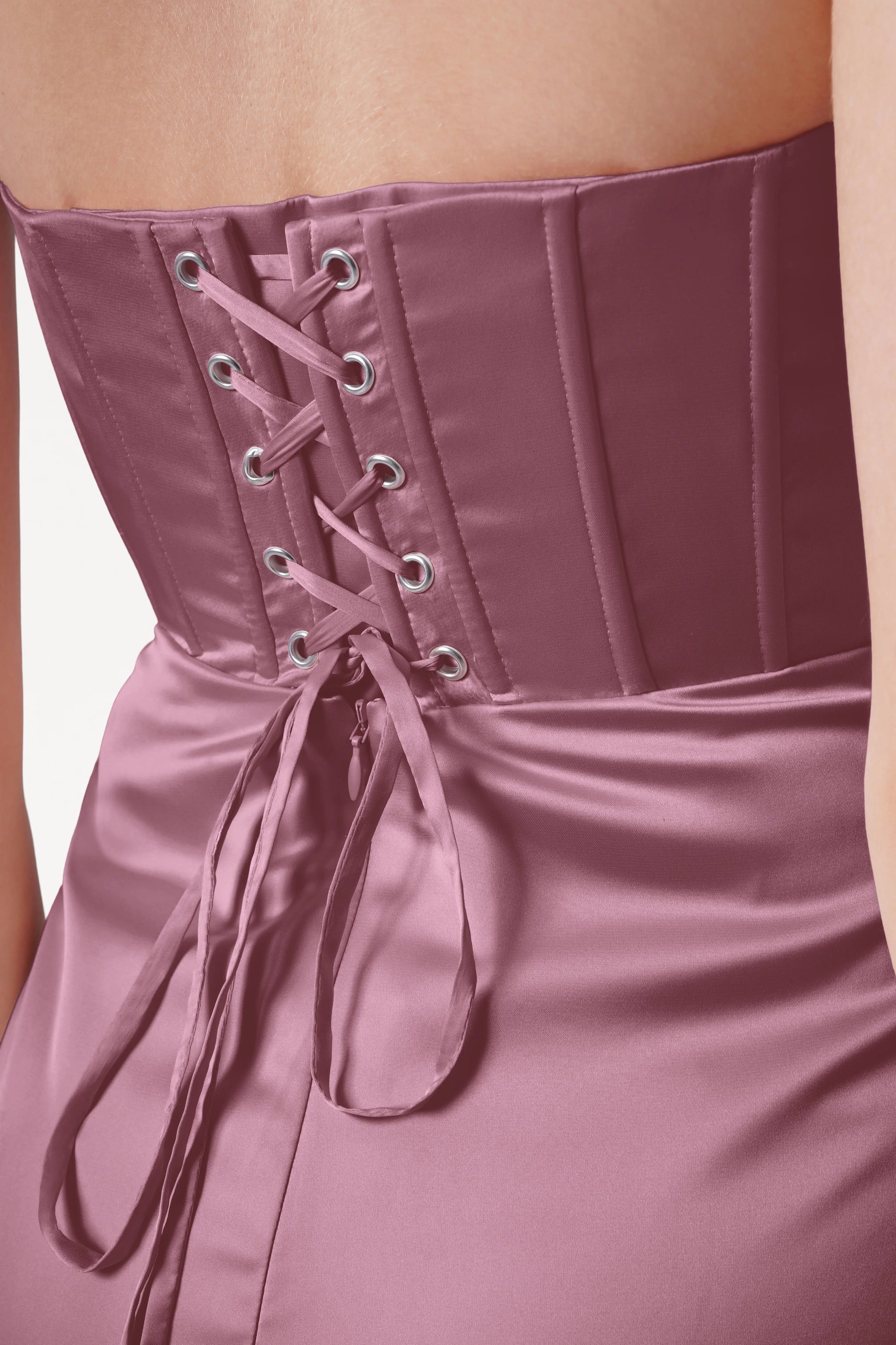 Close-up of a pink corset dress with lace-up back on a plain background