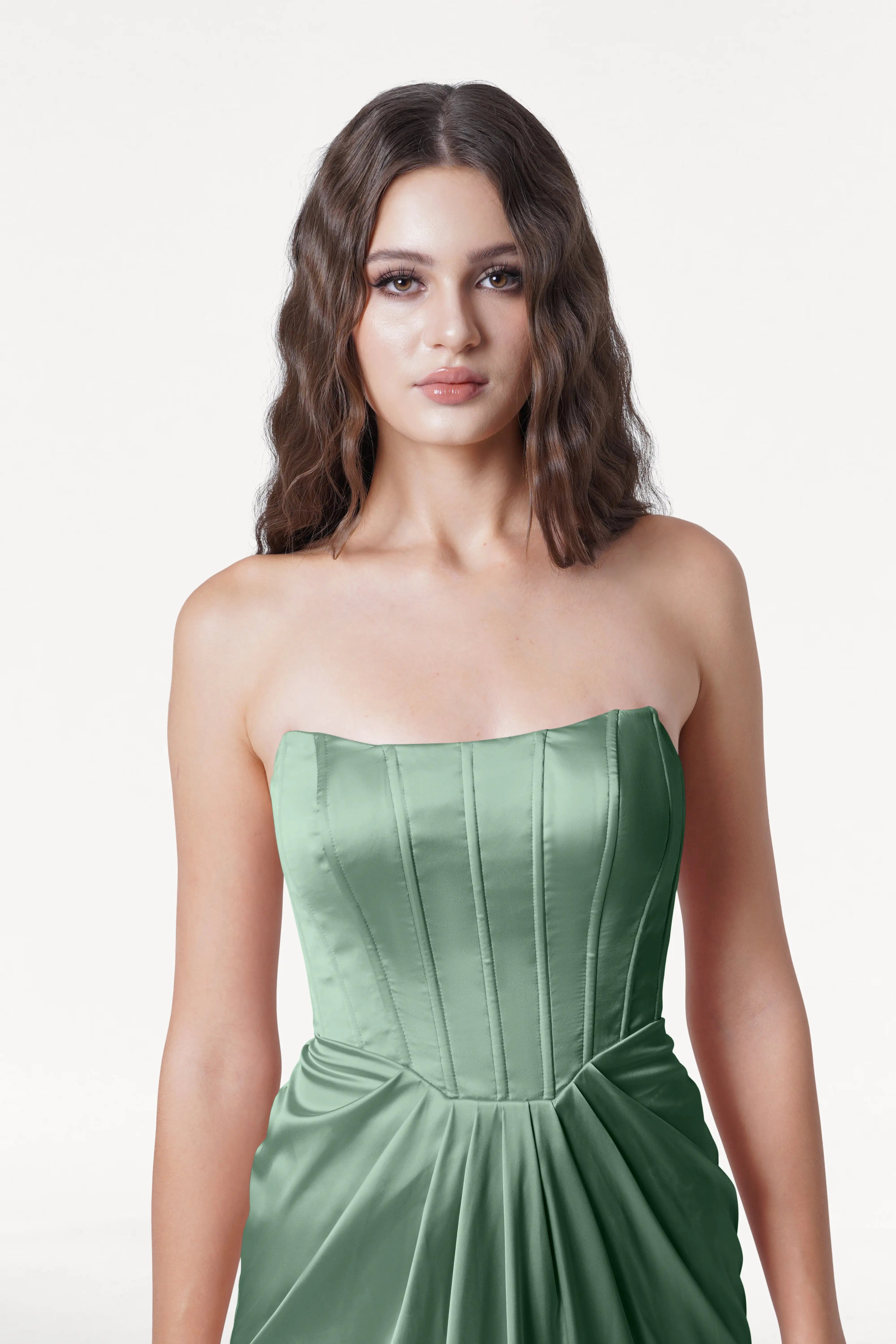 Woman wearing a strapless green dress on a white background