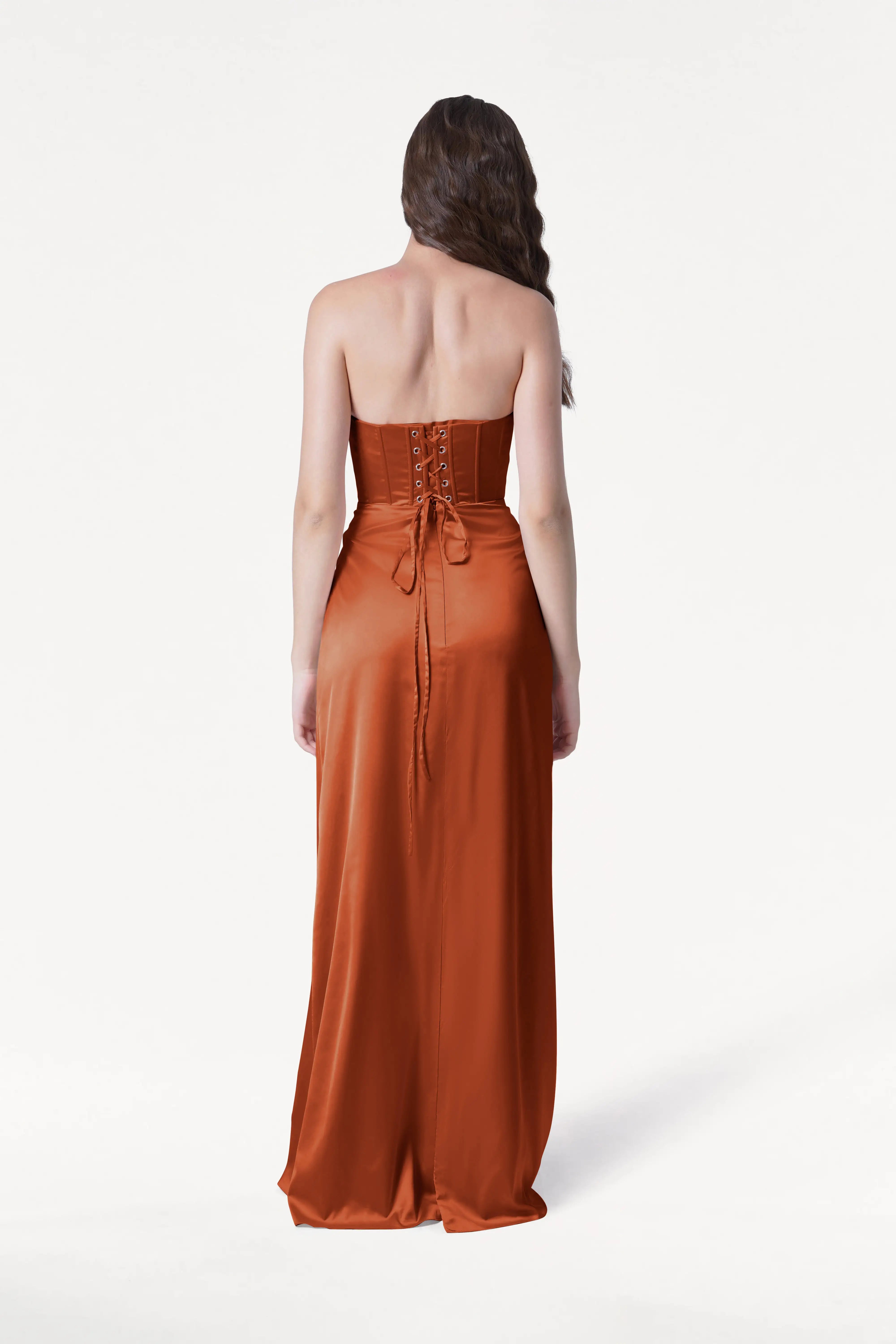 Woman wearing a strapless rust-colored dress on a white background
