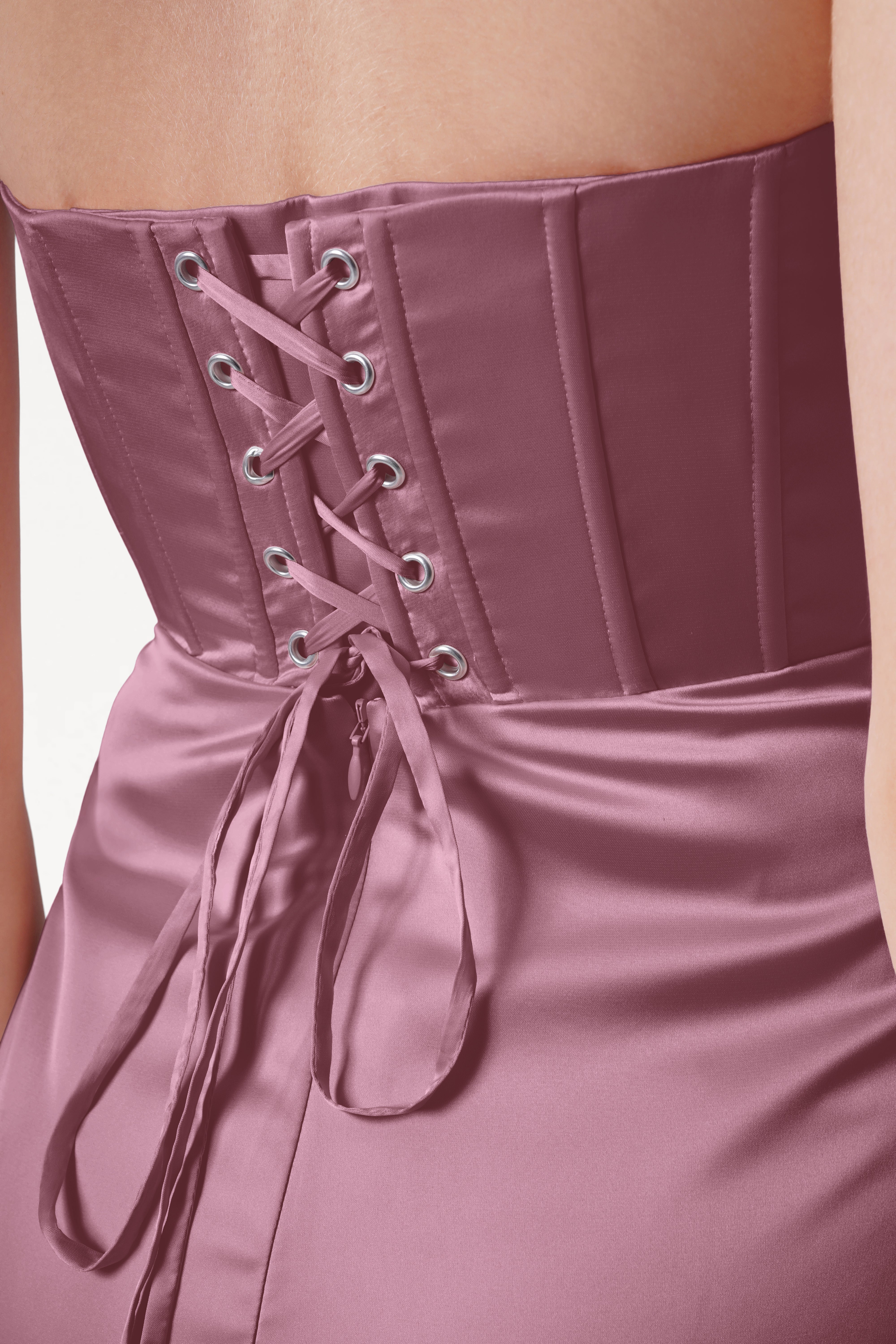 Close-up of a pink corset dress with lace-up back on a plain background