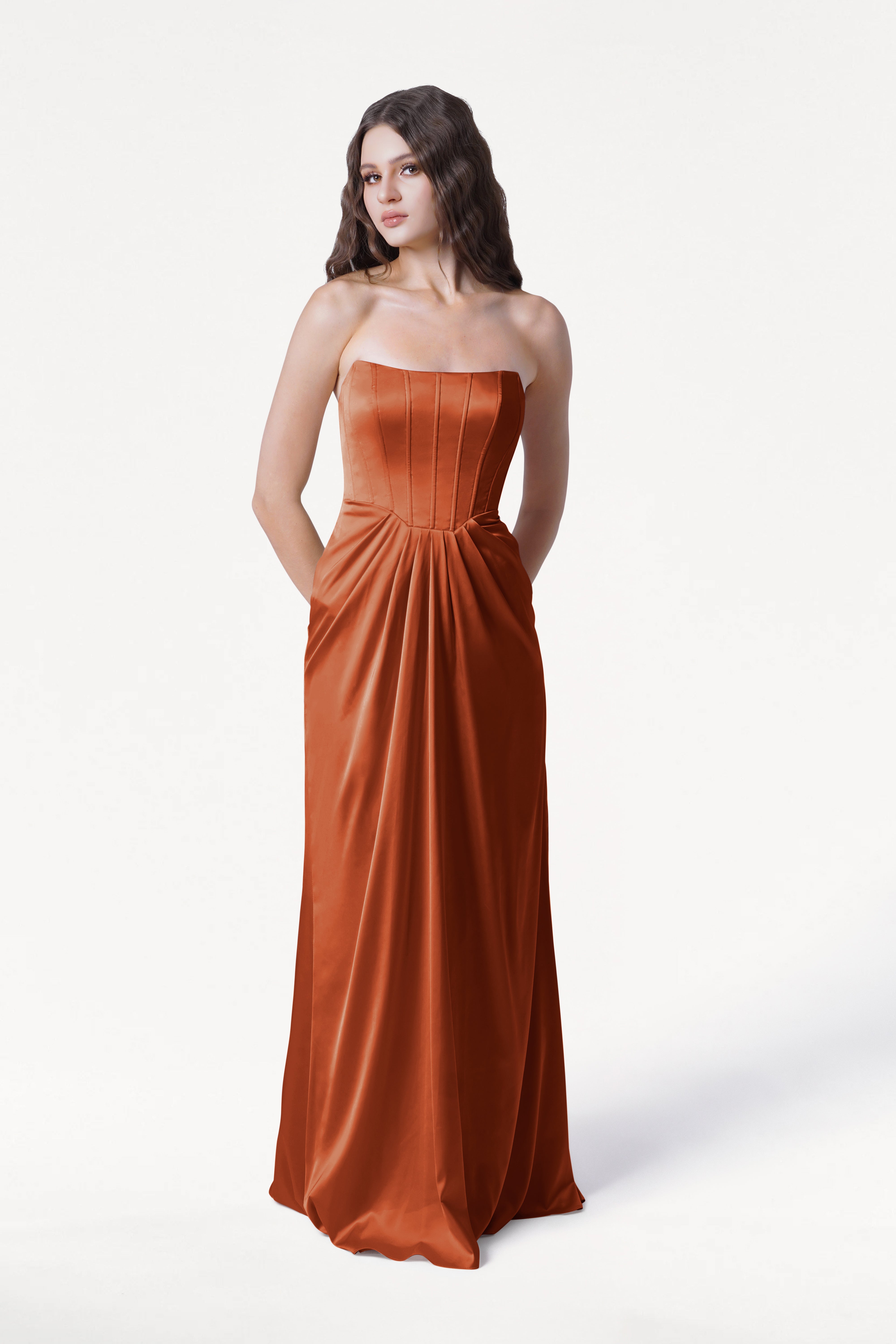 Woman wearing a strapless burnt orange colored evening gown on a white background