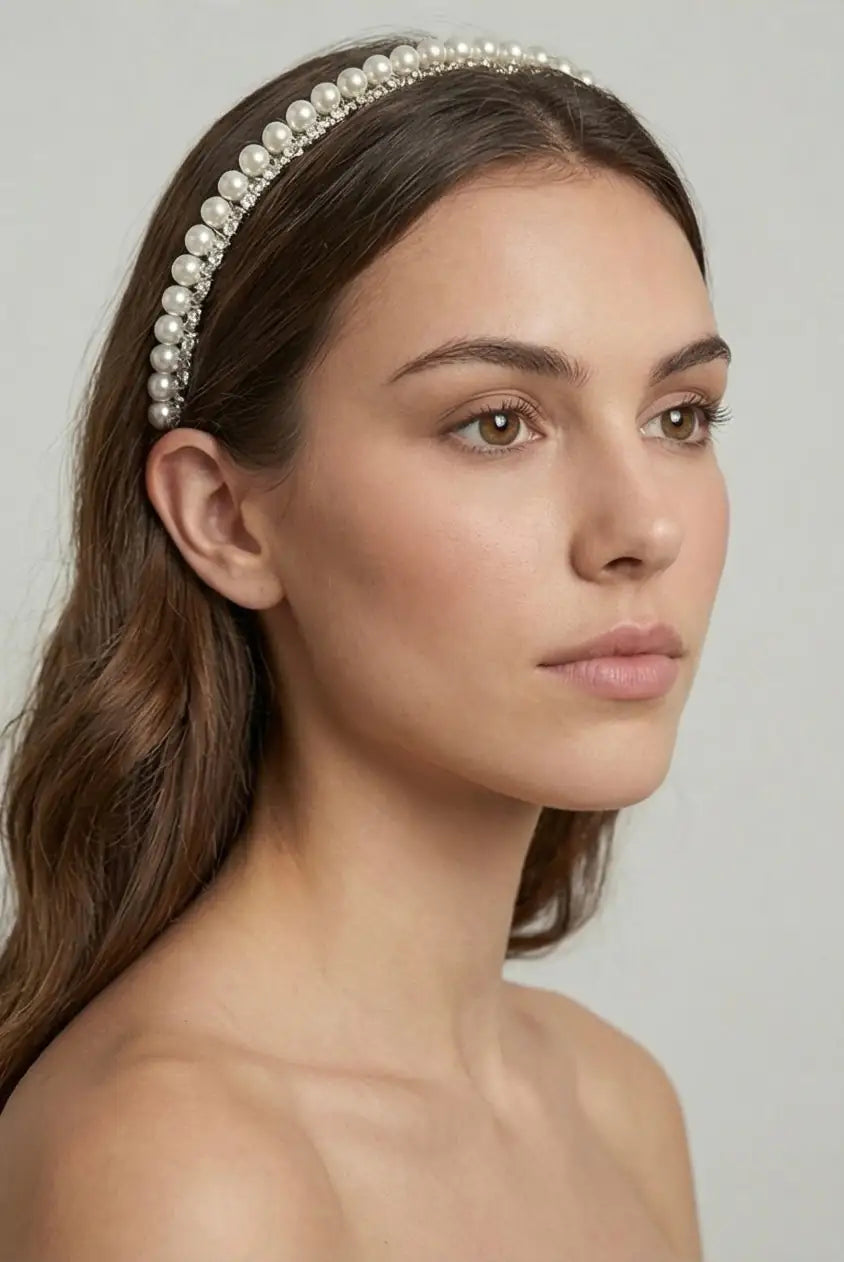A woman with long brown hair wears the TH&TH Seraphine Crystal Headband, looking slightly to the side. With a neutral expression and bare shoulders against a light background, this elegant piece is the perfect wedding hair accessory.