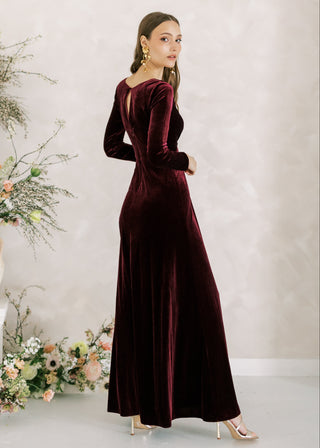 Woman wearing a burgundy velvet dress with floral decorations in the background