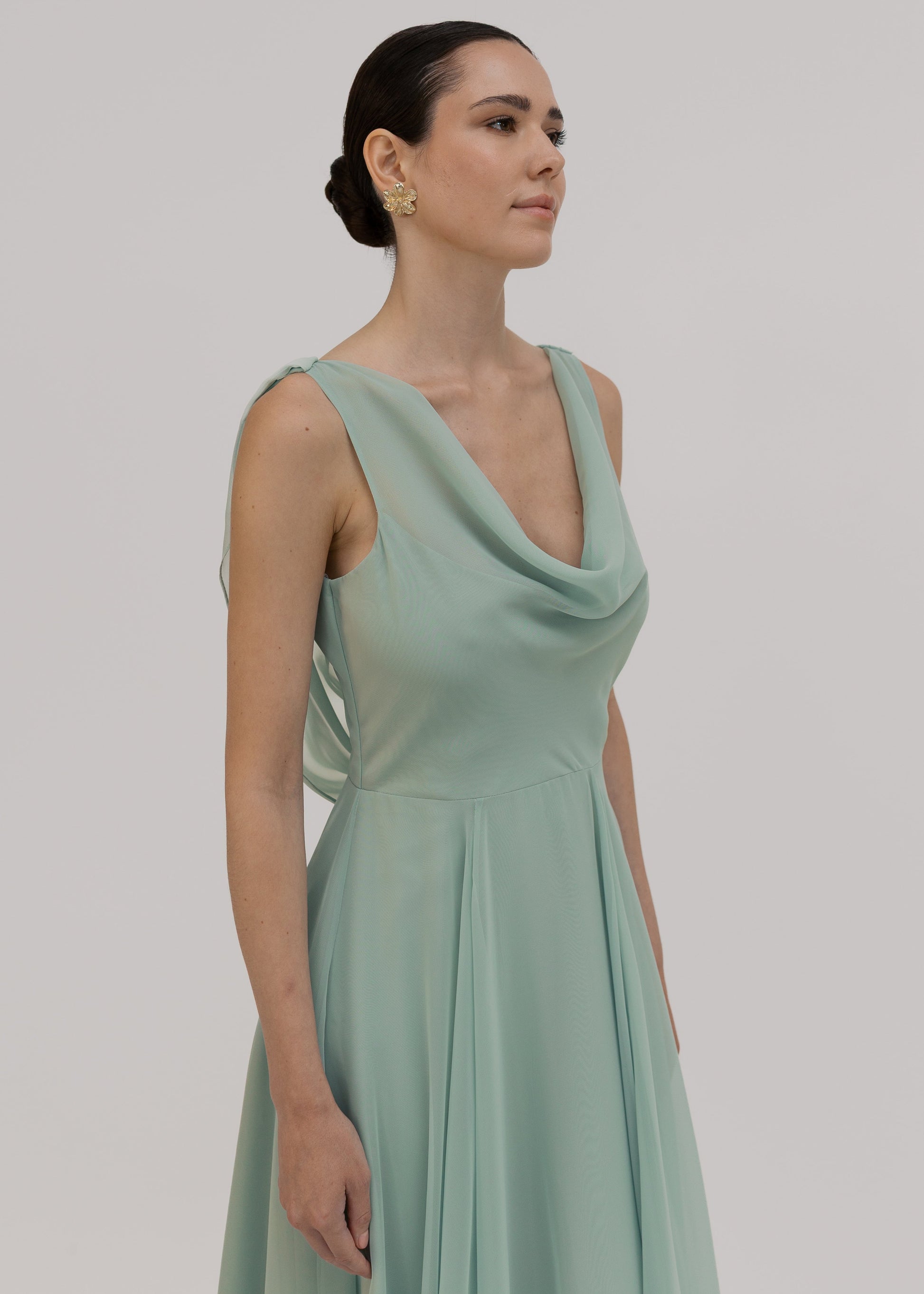 Woman wearing a light green dress close up of the cowl neck detail against a plain background dress by TH&TH Bridesmaids.