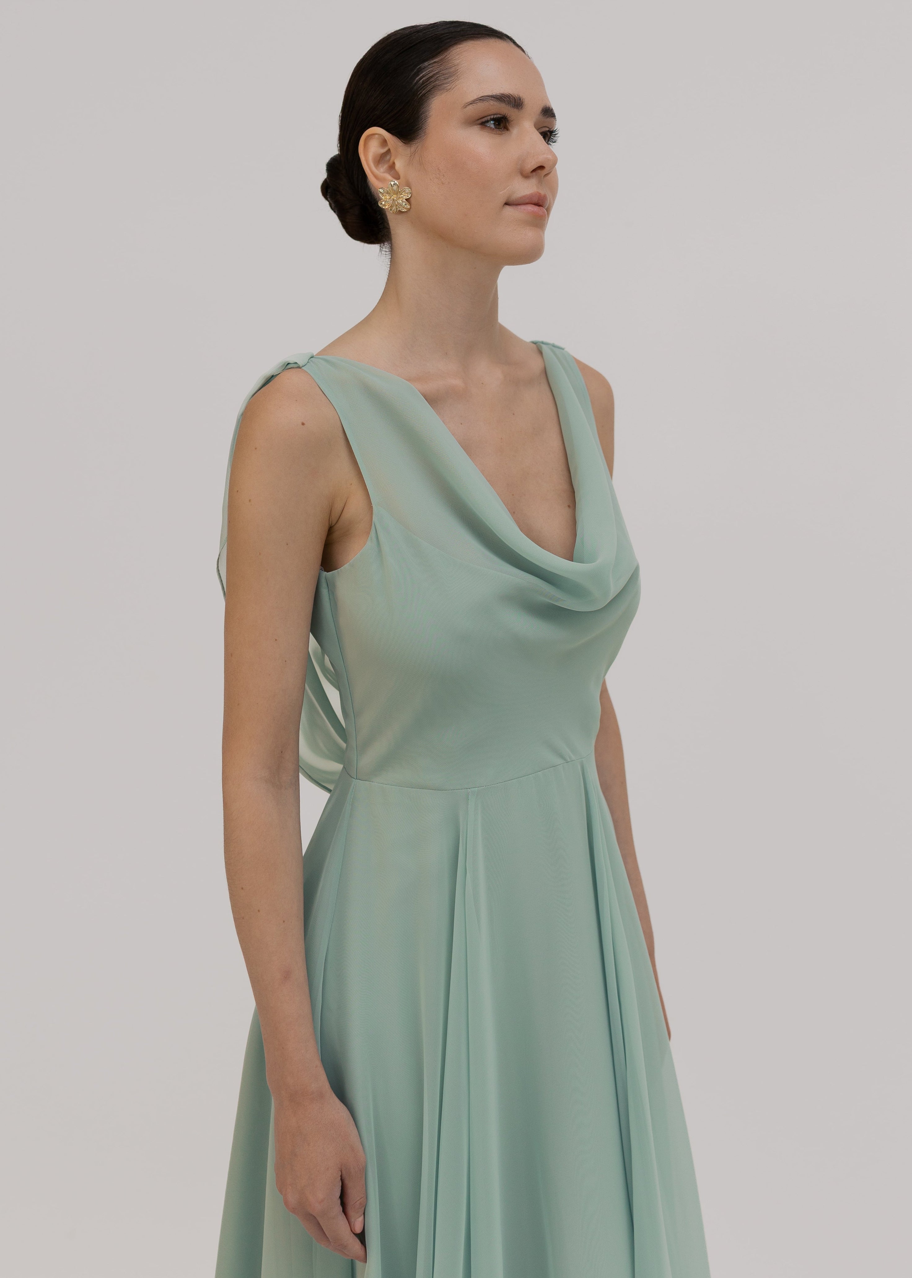 Woman wearing a light green dress close up of the cowl neck detail against a plain background dress by TH&TH Bridesmaids.