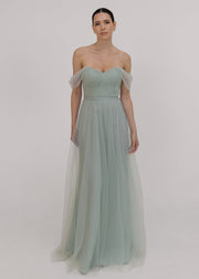 Model wearing Light green bridesmaid dress by TH&TH bridesmaid in a photo studio smiling. 