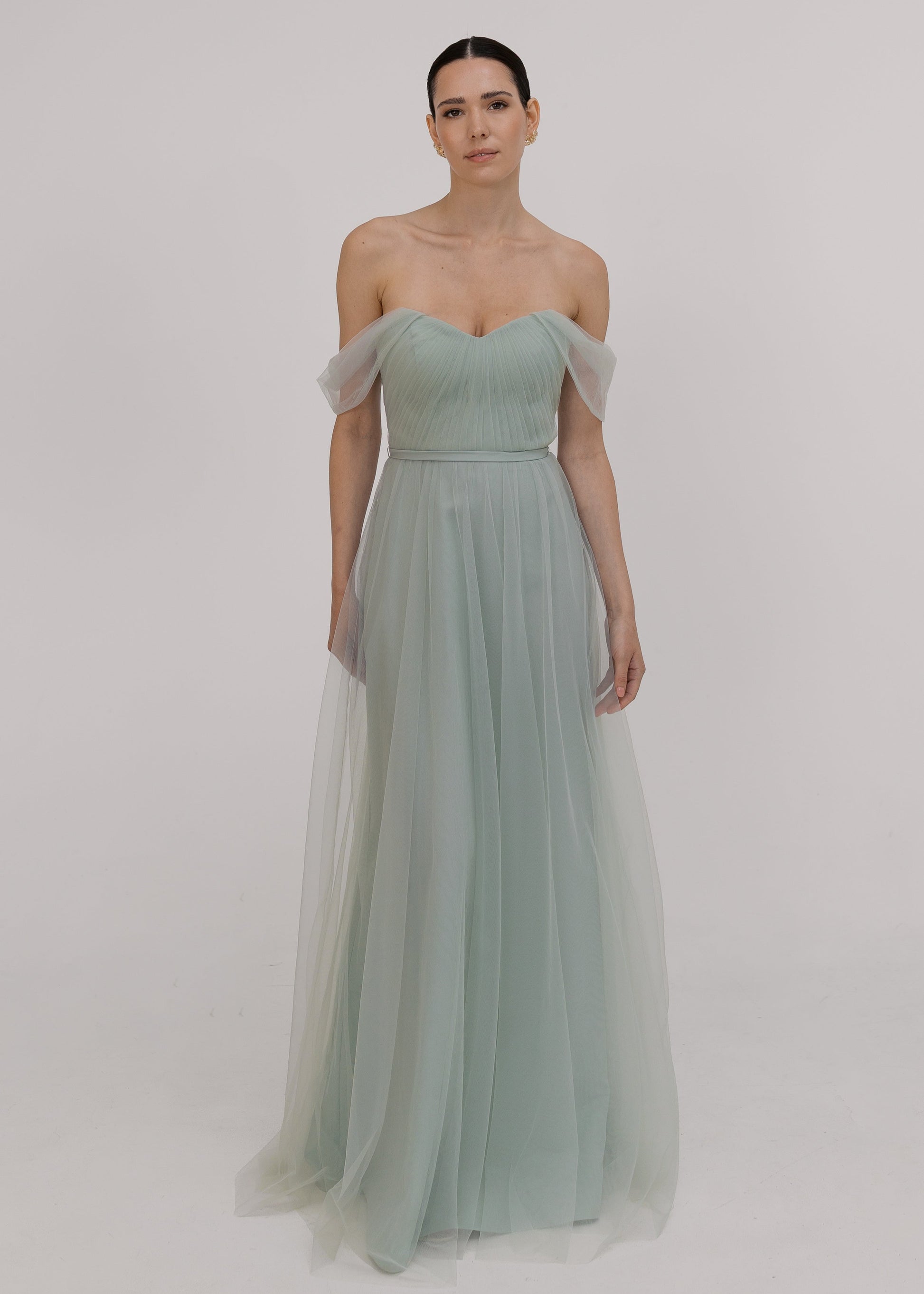 Model wearing Light green bridesmaid dress by TH&TH bridesmaid in a photo studio smiling. 