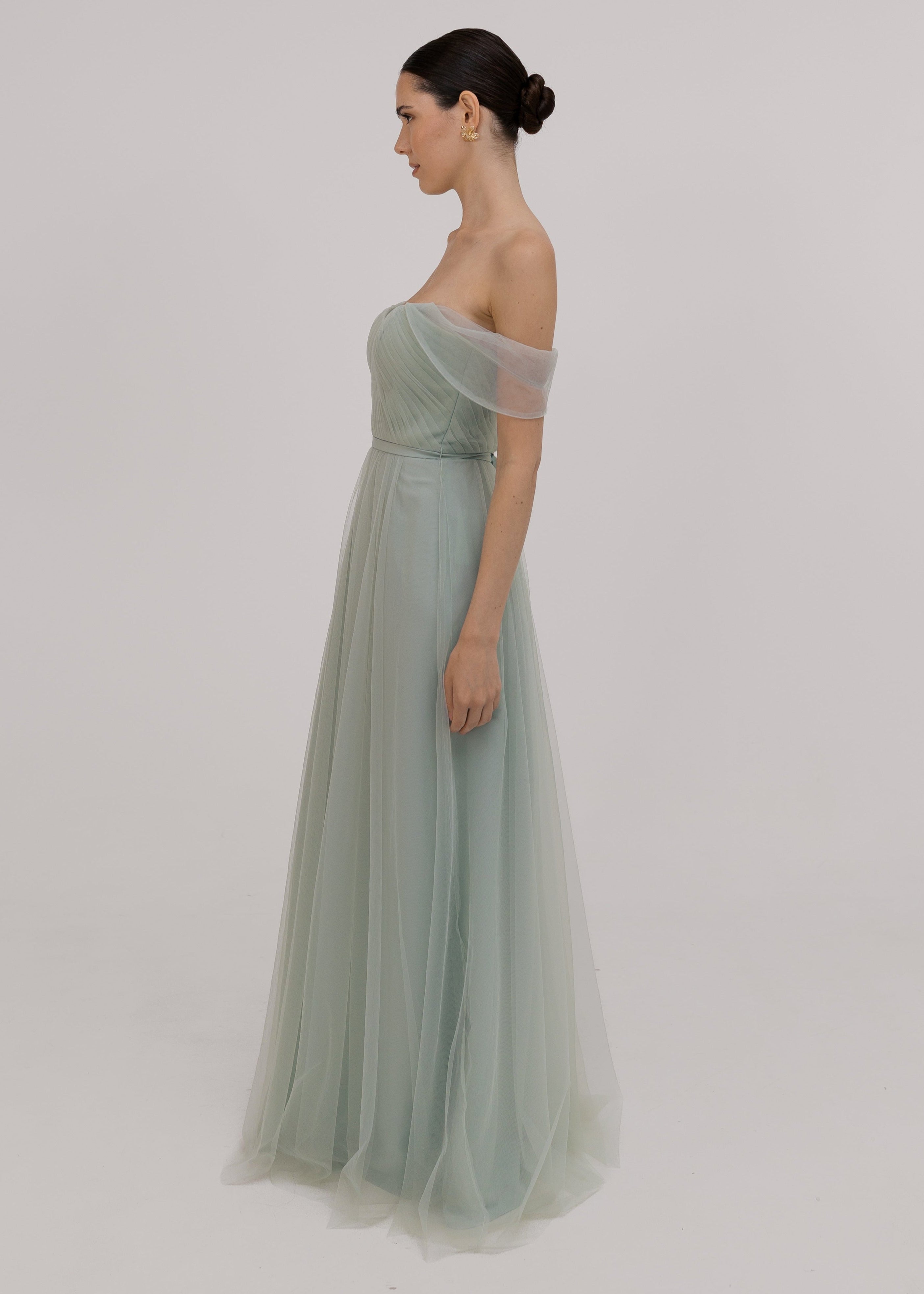 Model wears light green bridesmaid dress, side view with sleeves over top shoulder by TH&TH.