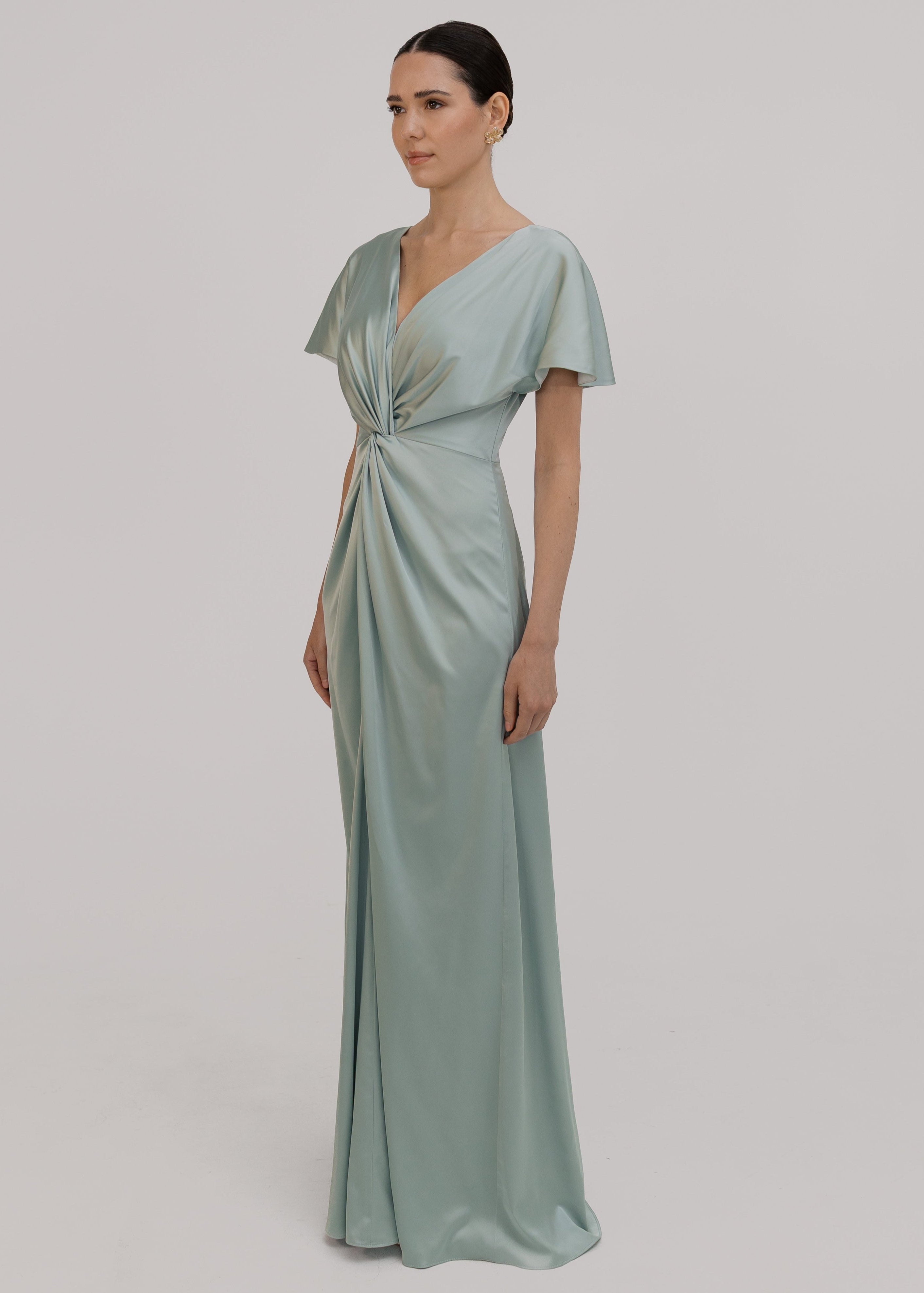 Woman wearing a green bridesmaid dress with twist detail at front, side angle view by TH&TH.