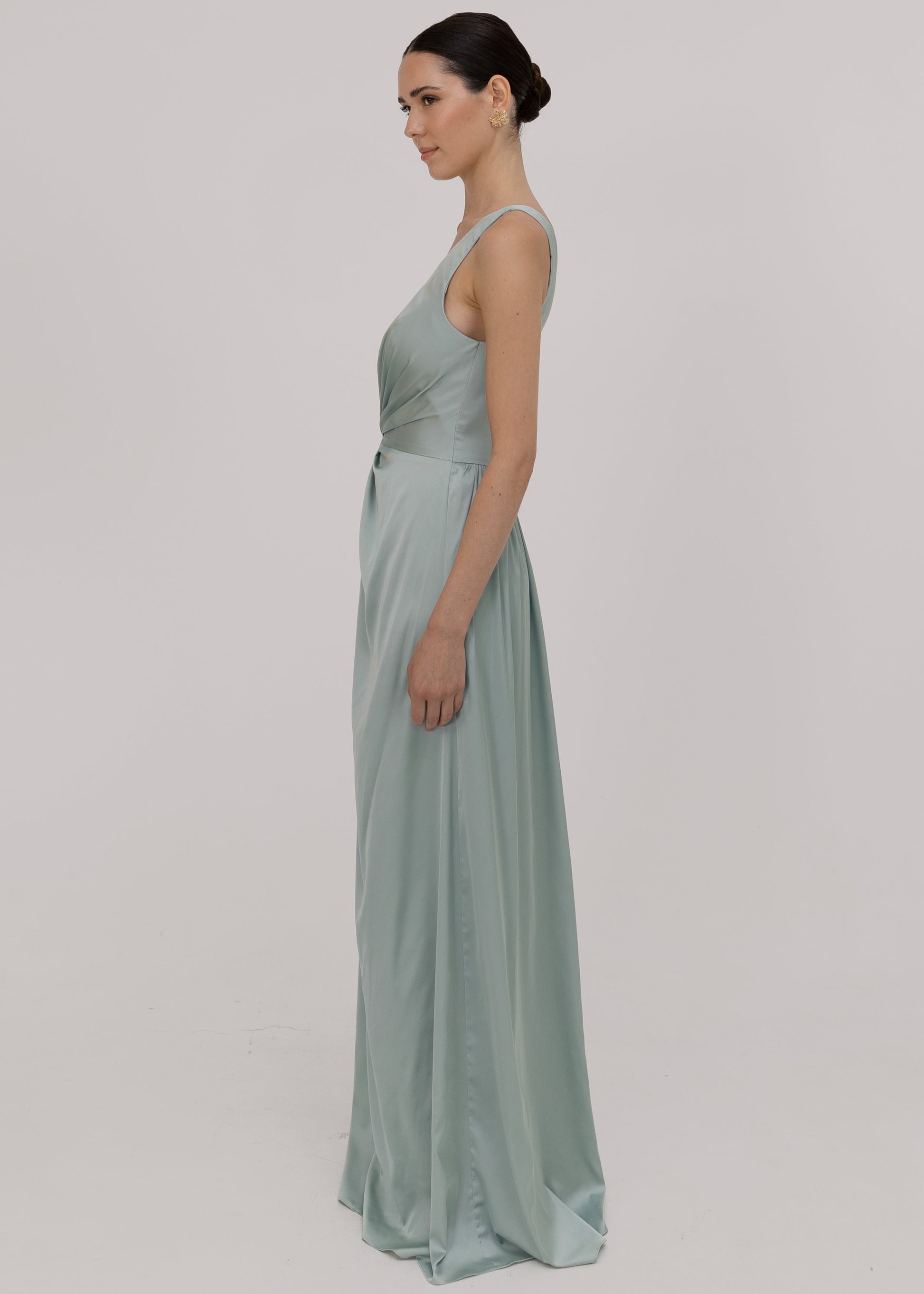 Woman wearing a green bridesmaid dress with one shoulder detail side view by TH&TH. 