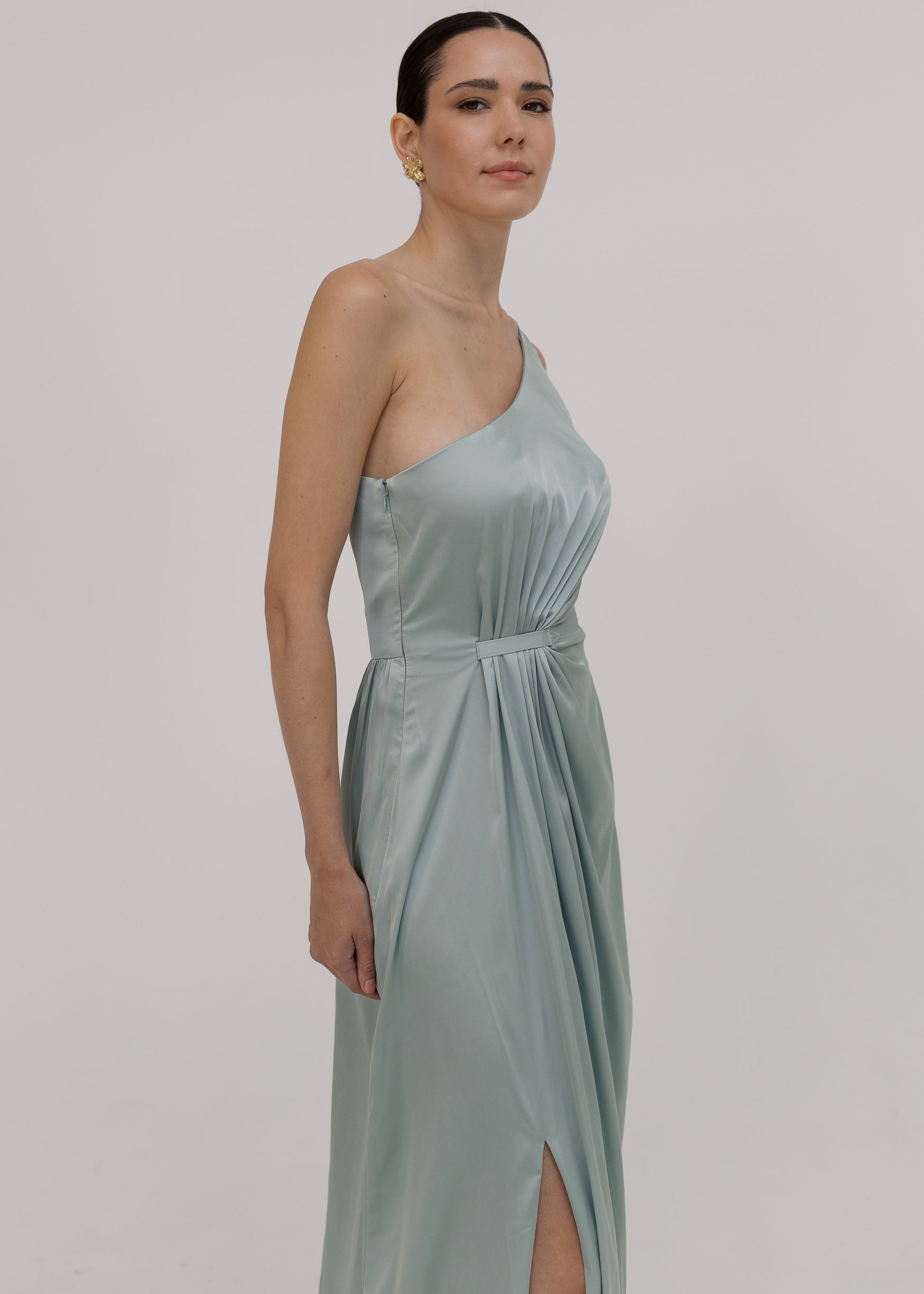 Woman wearing a green bridesmaid dress with one shoulder detail and gathers at side by TH&TH bridesmaids.