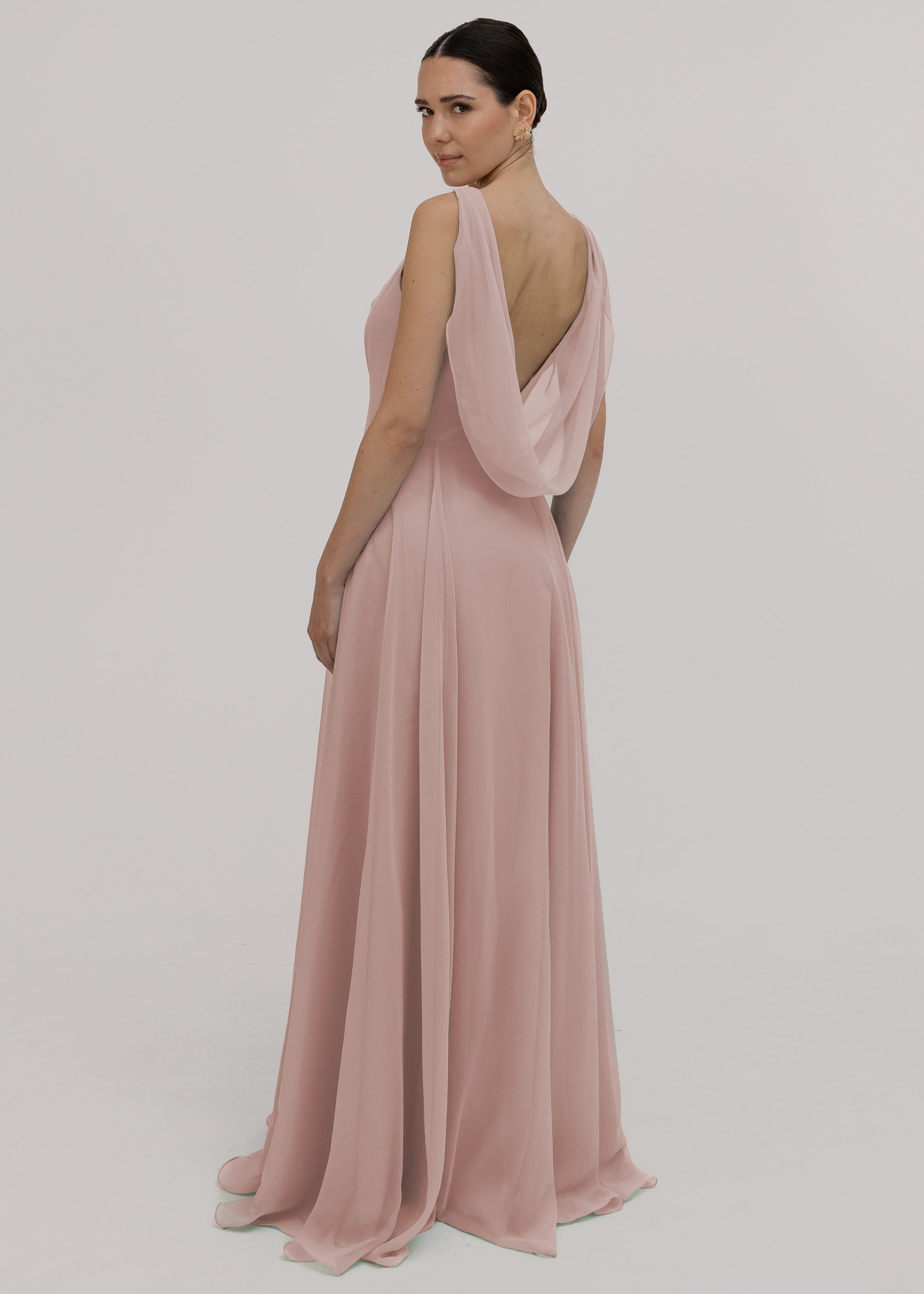 Model wearing a blush pink bridesmaid dress in chiffon with low cowl back and flowing chiffon skirt by TH&TH Bridesmaids.
