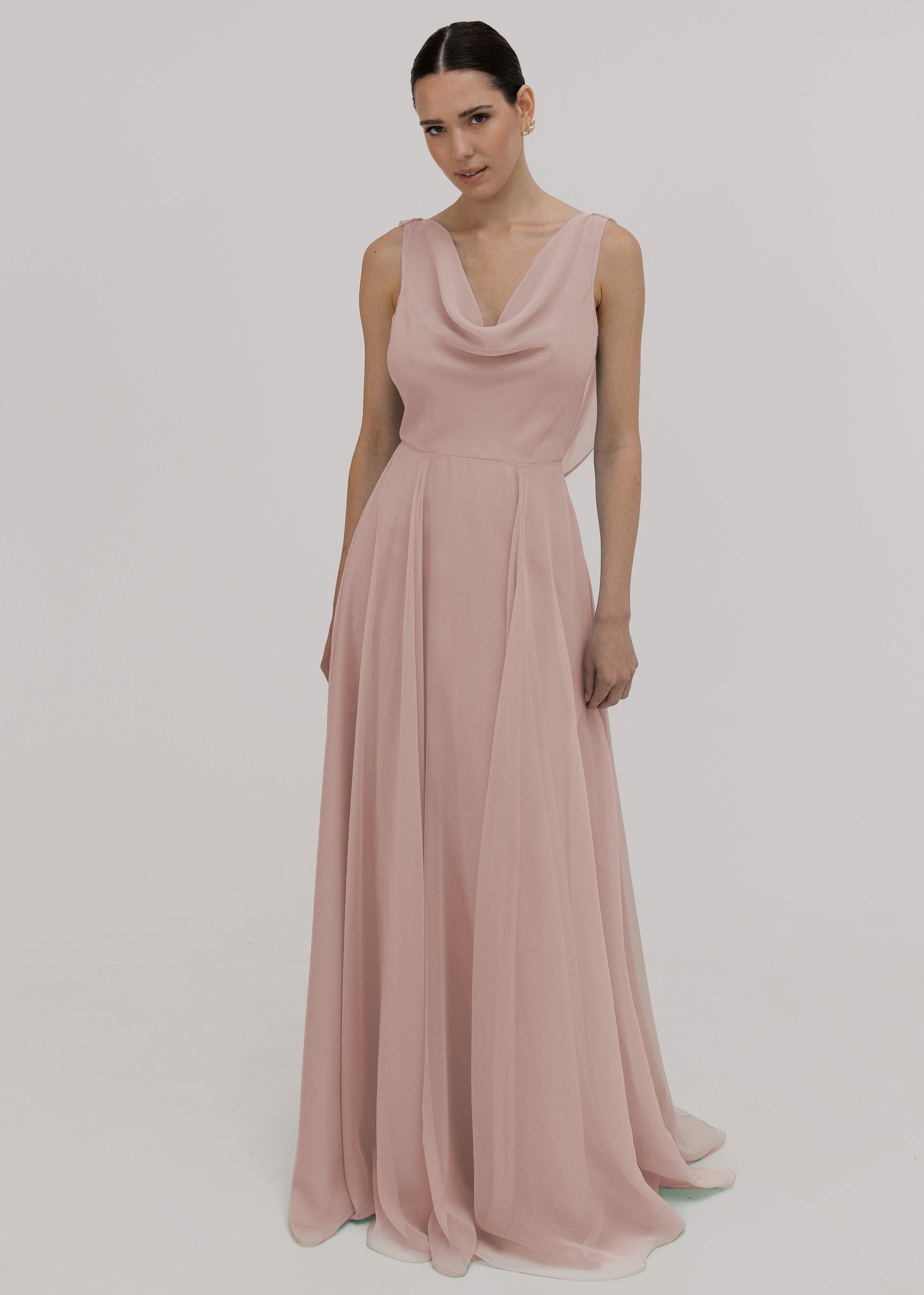 Model wearing a blush pink bridesmaid dress in chiffon with cowl neckline and flowing chiffon skirt by TH&TH Bridesmaids.