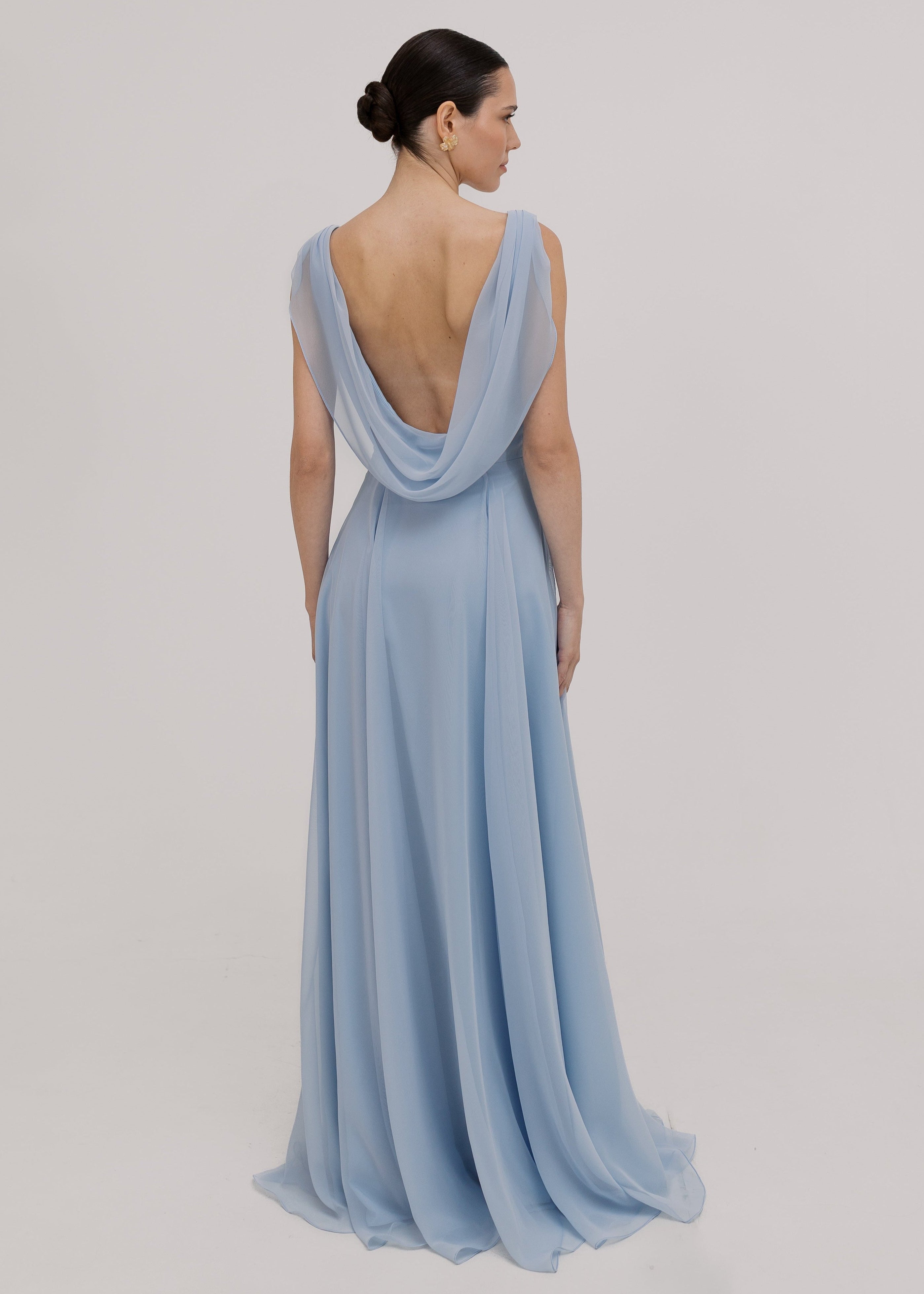 Model wearing a dusty blue bridesmaid dress in chiffon with low cowl back and flowing chiffon skirt by TH&TH Bridesmaids.
