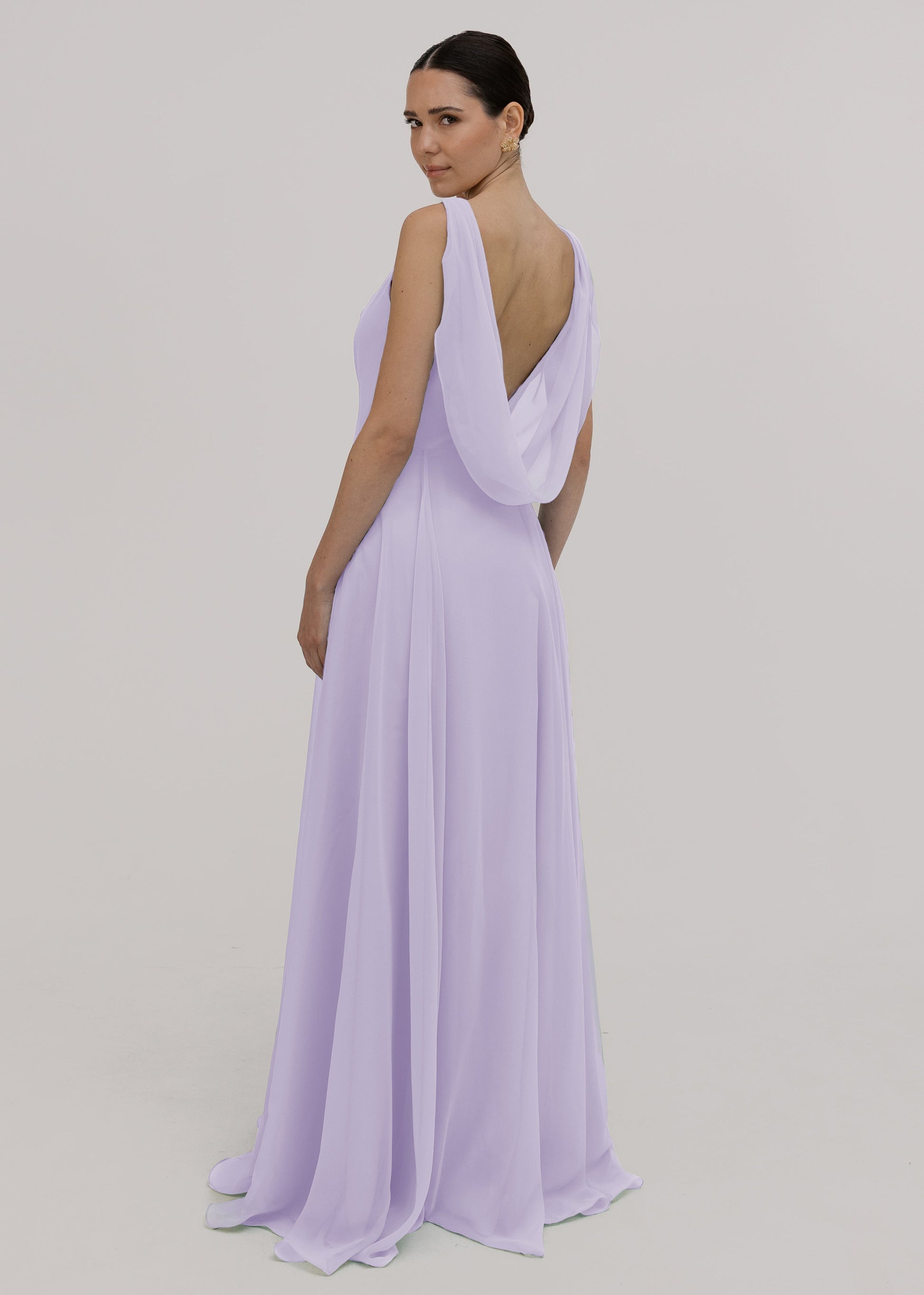 Model wearing a lilac bridesmaid dress in chiffon with cowl back and flowing chiffon skirt by TH&TH Bridesmaids.
