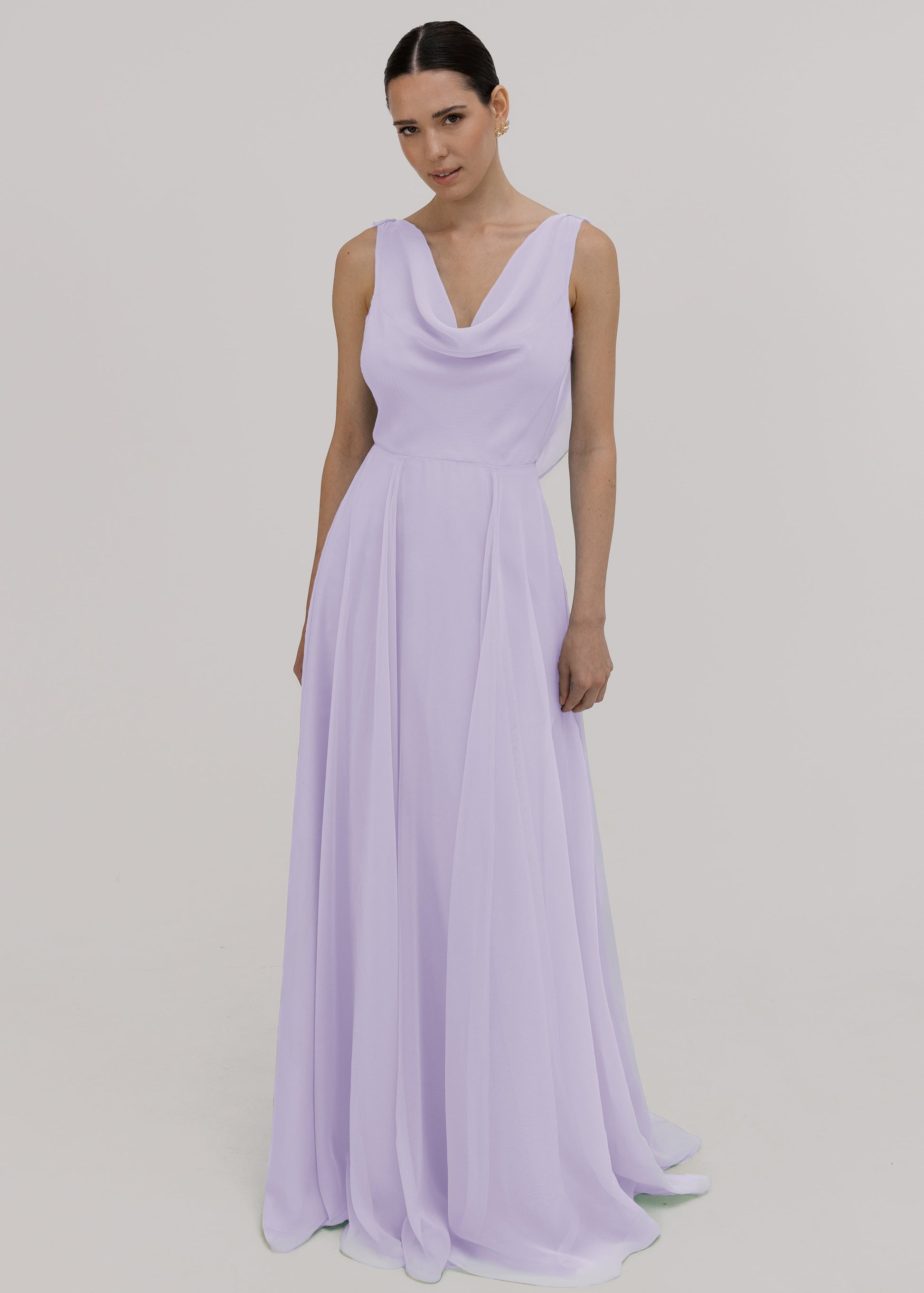 Model wearing a lilac bridesmaid dress in chiffon with cowl neckline and flowing chiffon skirt by TH&TH Bridesmaids.
