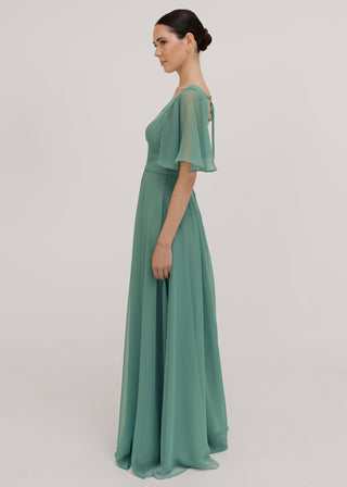 Model wears a sage green bridesmaid dress in chiffon with v front neckline, flutter sleeves and flowing chiffon skirt by TH&TH Bridesmaids. 
