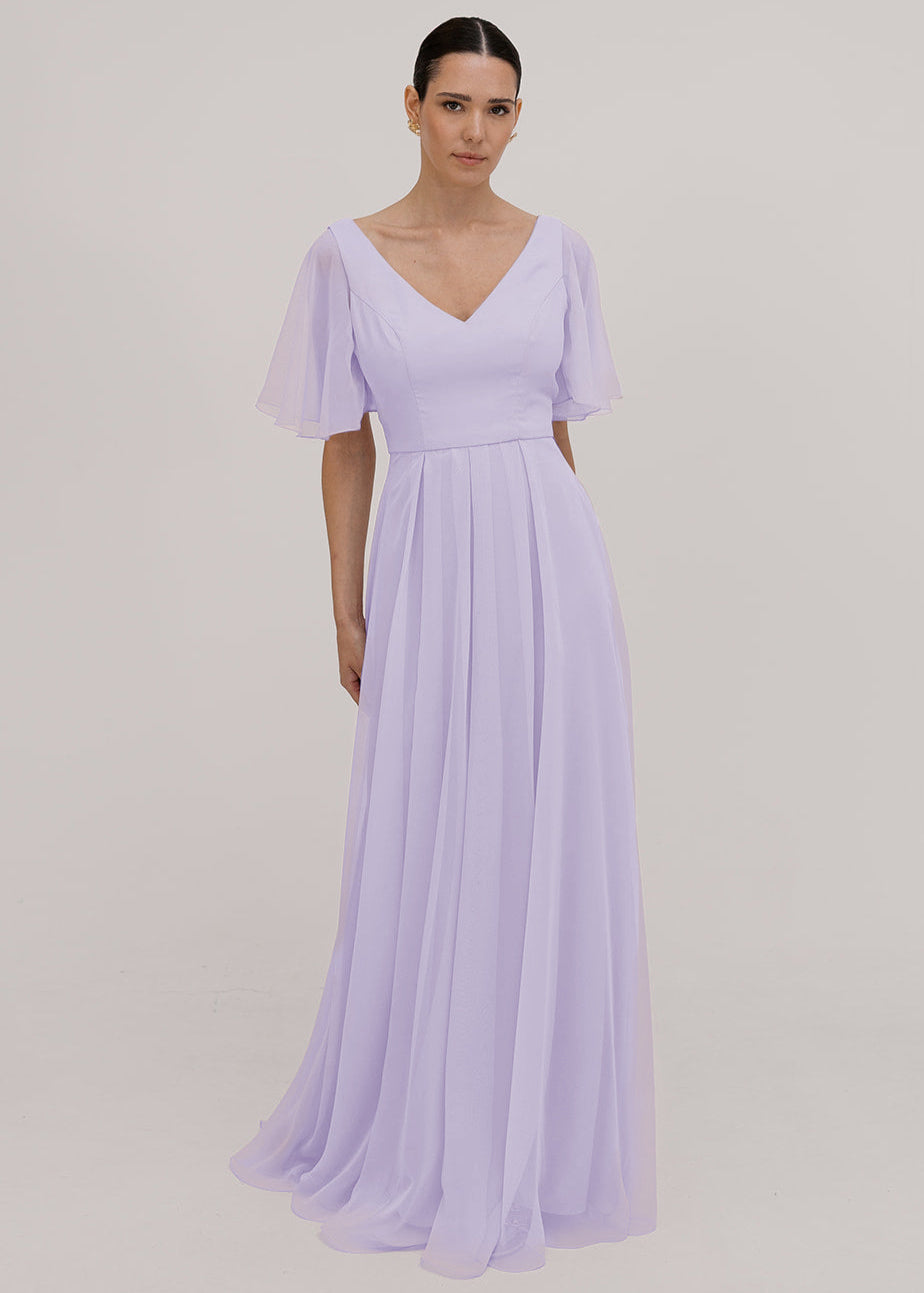 Model wears a lilac bridesmaid dress in chiffon with v front neckline, flutter sleeves and flowing chiffon skirt by TH&TH Bridesmaids. 