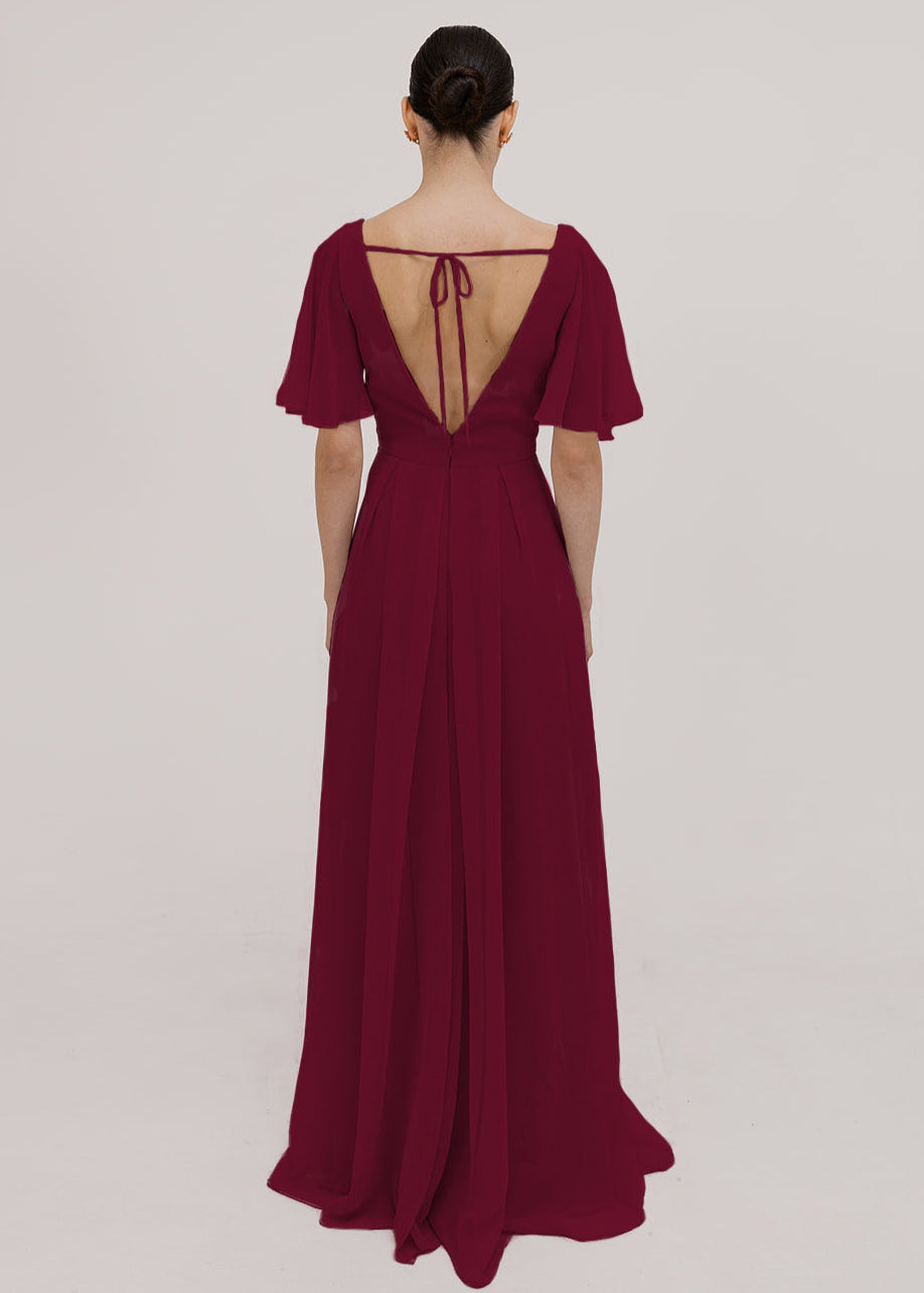 Model wears a merlot bridesmaid dress in chiffon with low back, flutter sleeves and flowing chiffon skirt by TH&TH Bridesmaids. 
