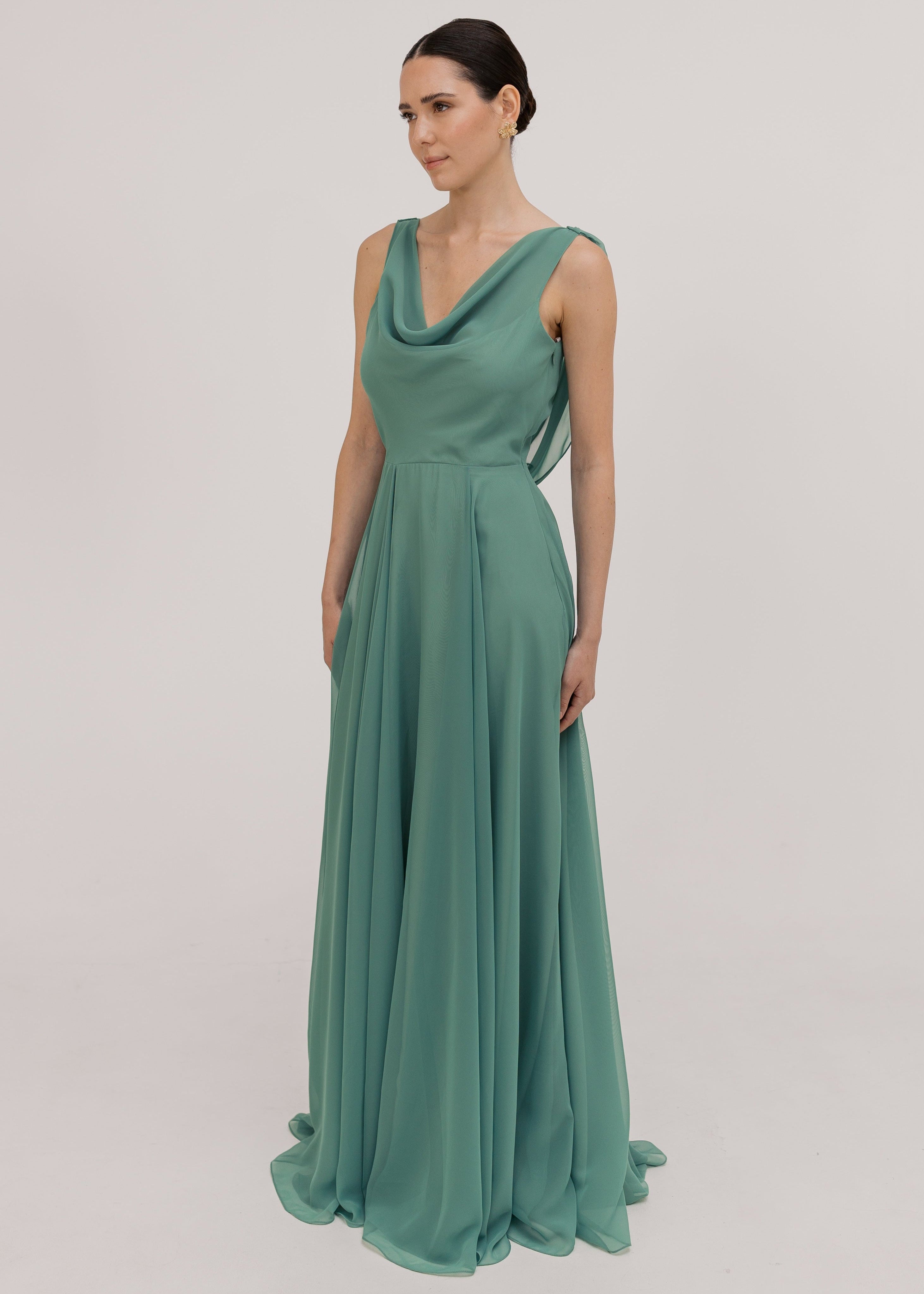 Model wearing a sage green bridesmaid dress with cowl neckline and flowing chiffon skirt by TH&TH Bridesmaids.