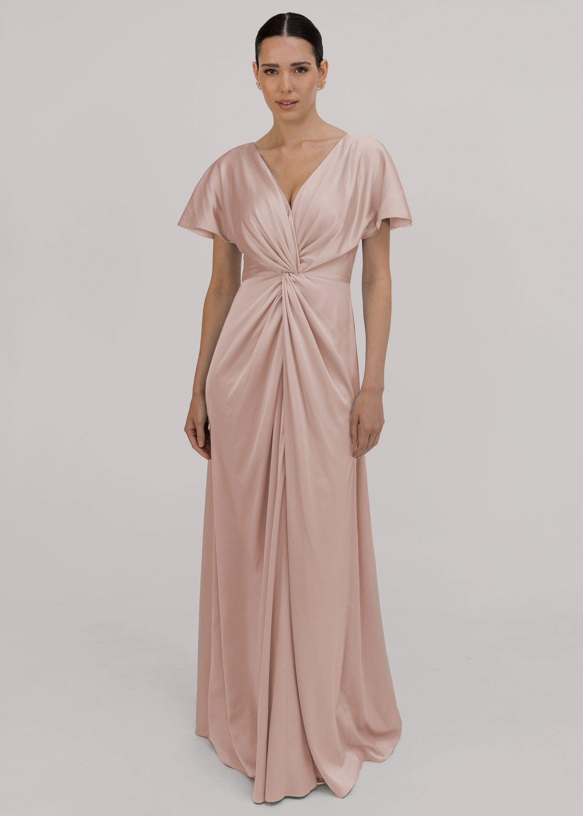 A blush pink satin bridesmaid dress with v twist front neckline, flutter sleeves on a white background by TH&TH Bridesmaids. 
