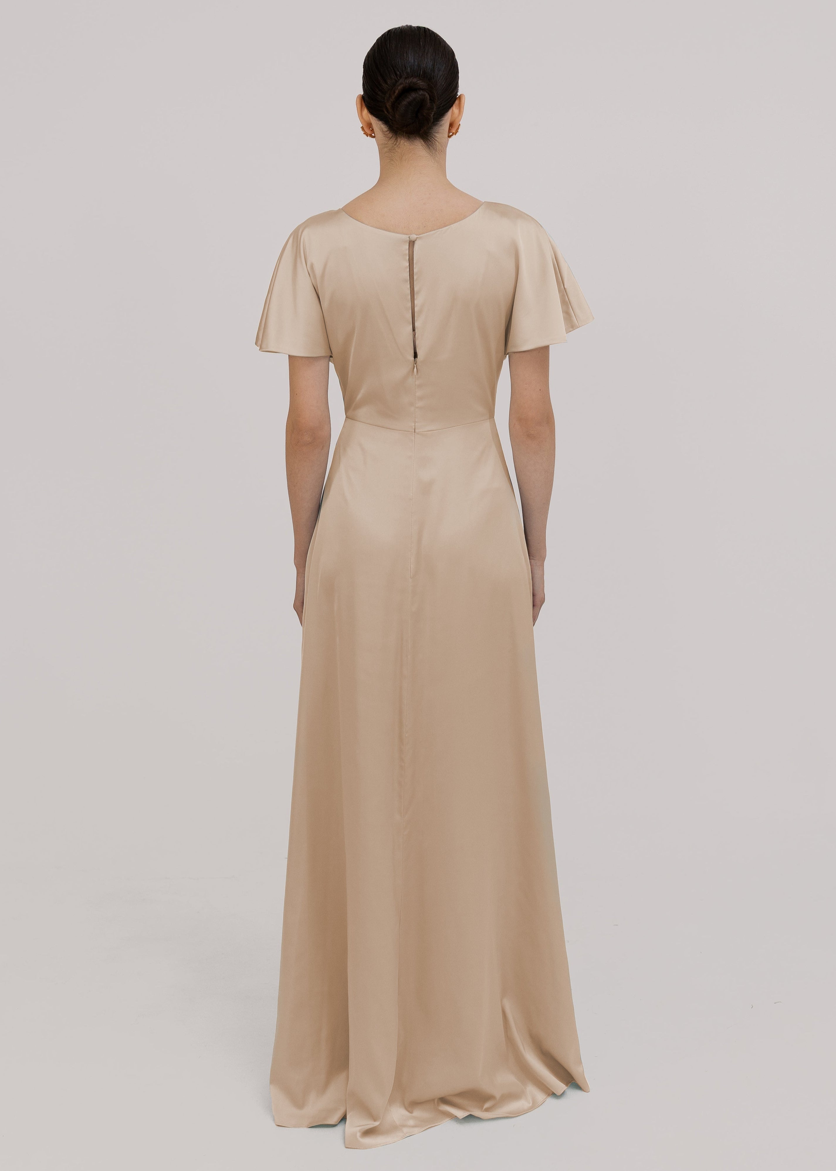 Model wears a champagne satin bridesmaid dress with flutter sleeves on a white background by TH&TH Bridesmaids. 

