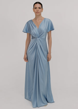 A woman wearing a dusty blue satin bridesmaid dress with v twist front neckline, flutter sleeves on a white background by TH&TH Bridesmaids.
