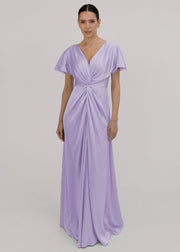 A woman wearing a lilac satin bridesmaid dress with v twist front neckline, flutter sleeves on a white background by TH&TH Bridesmaids. 
