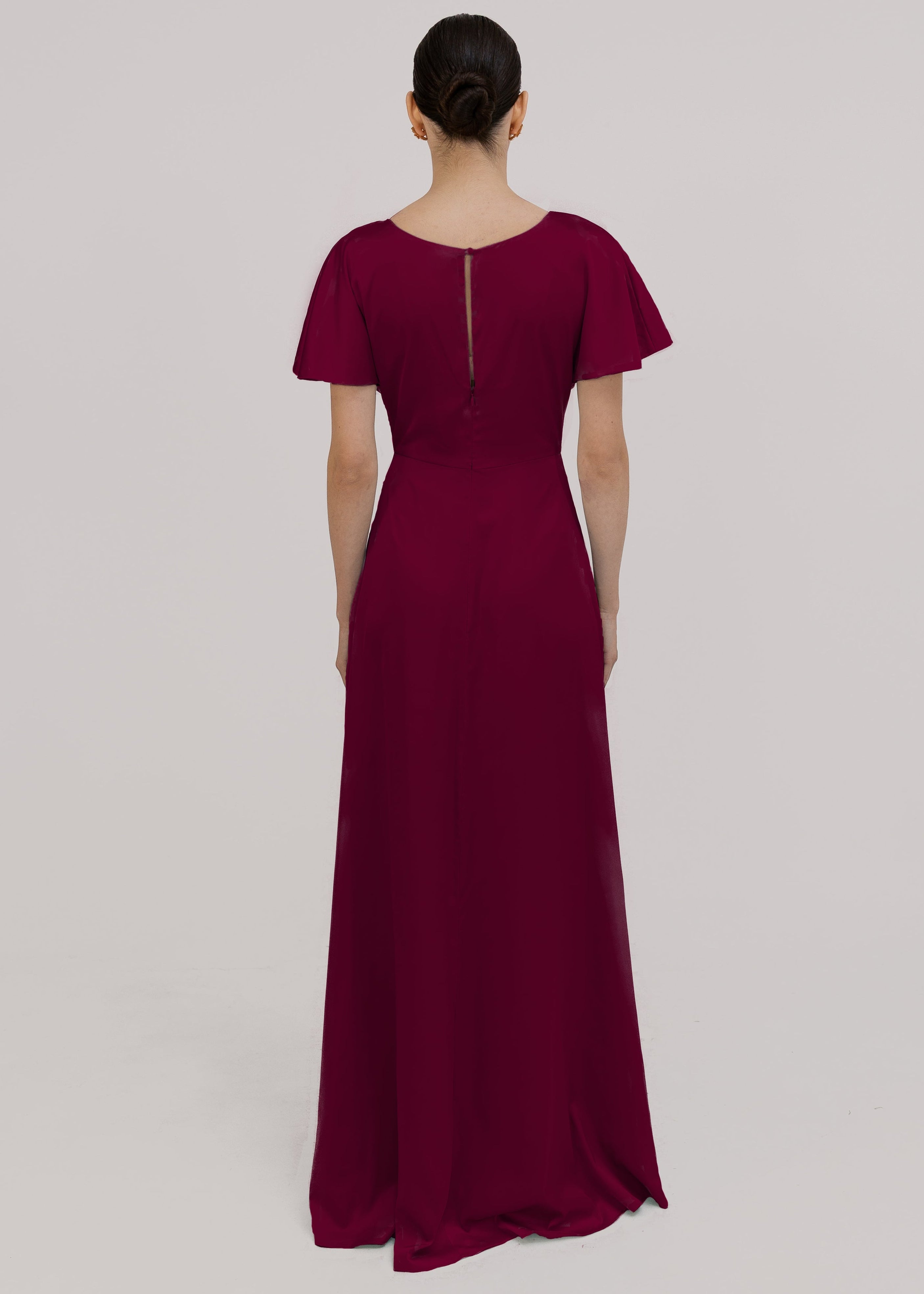 A woman wearing a merlot satin bridesmaid dress with v twist front neckline, flutter sleeves on a white background by TH&TH Bridesmaids.
