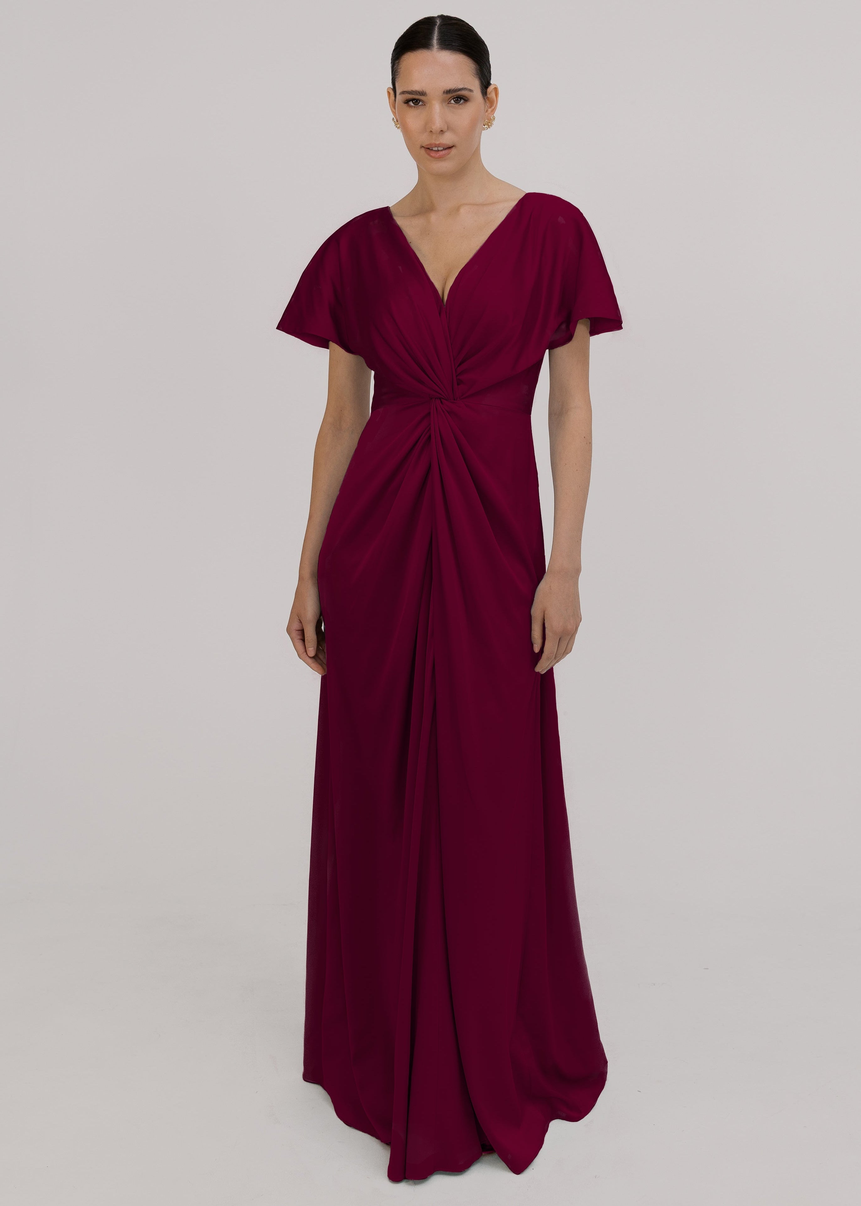 A woman wearing a merlot satin bridesmaid dress with v twist front neckline, flutter sleeves on a white background by TH&TH Bridesmaids.
