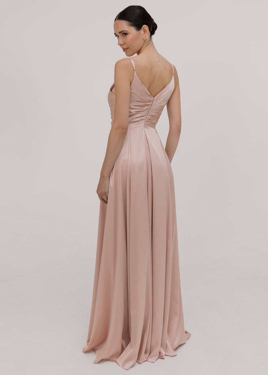 Model wearing a floor length blush pink satin bridesmaid dress with V back and spaghetti straps by TH&TH Bridesmaids.
