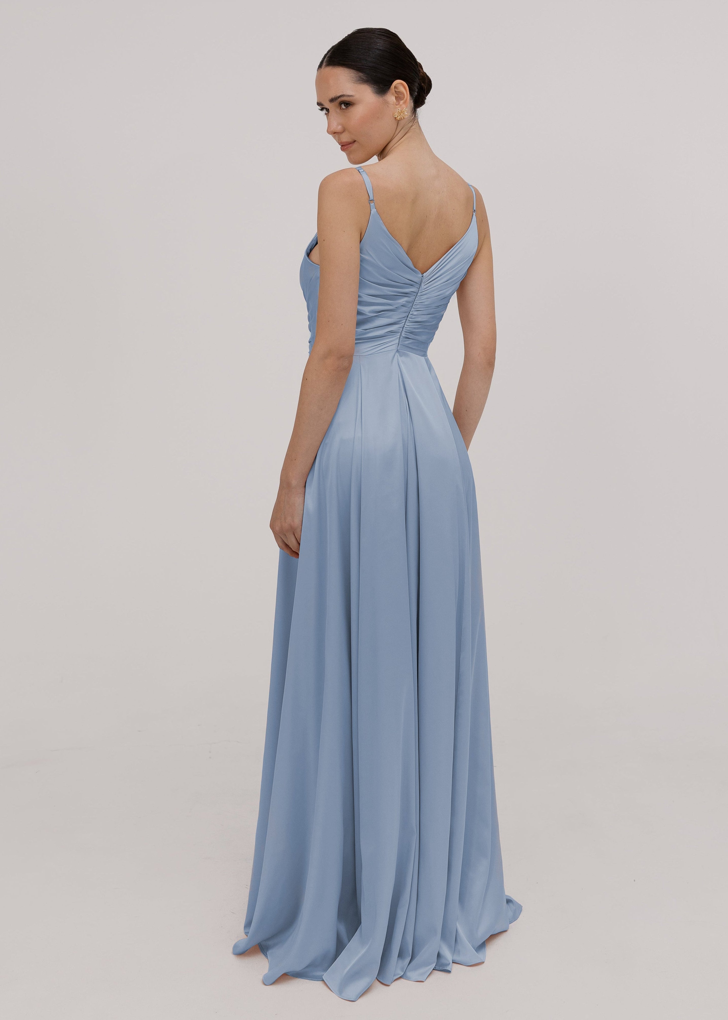Model wearing a floor length dusty blue bridesmaid dress with V back and spaghetti straps by TH&TH Bridesmaids.