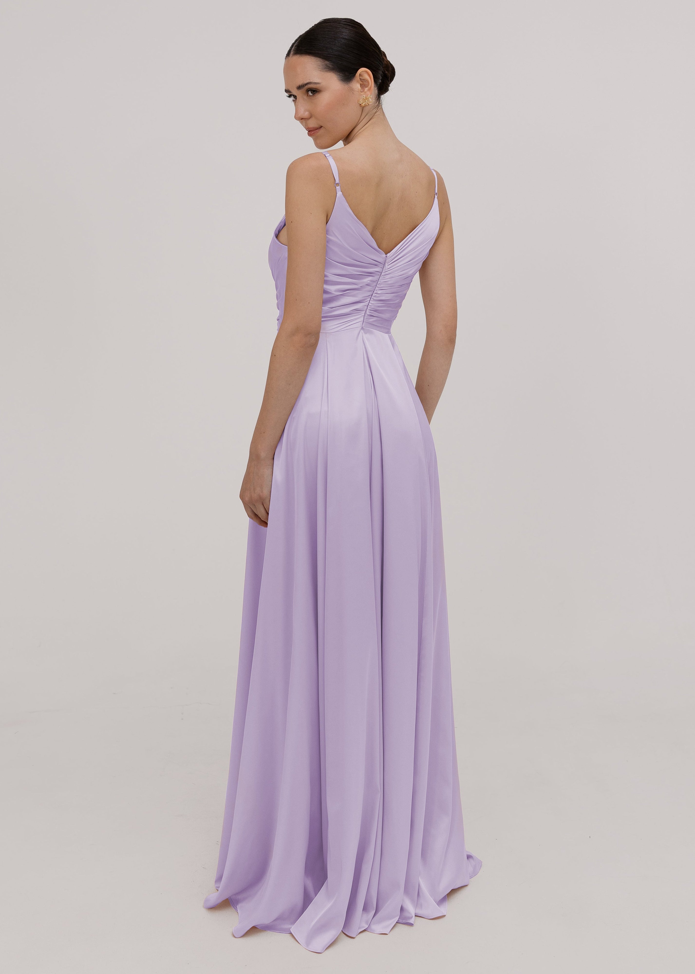 Model wearing a floor length lilac satin bridesmaid dress with V back and spaghetti straps by TH&TH Bridesmaids.
