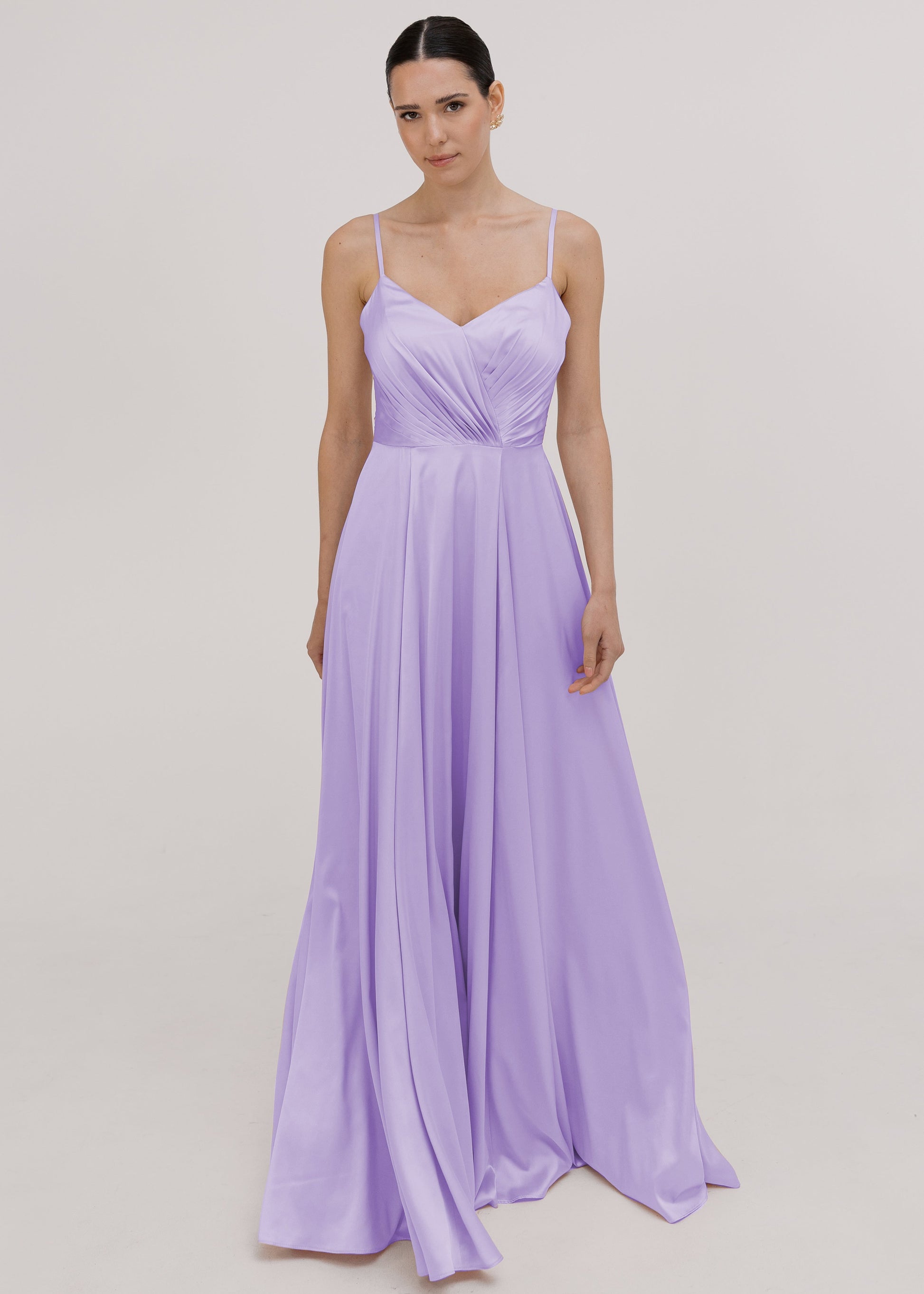 Model wearing a floor length lilac satin bridesmaid dress with V back and spaghetti straps by TH&TH Bridesmaids.
