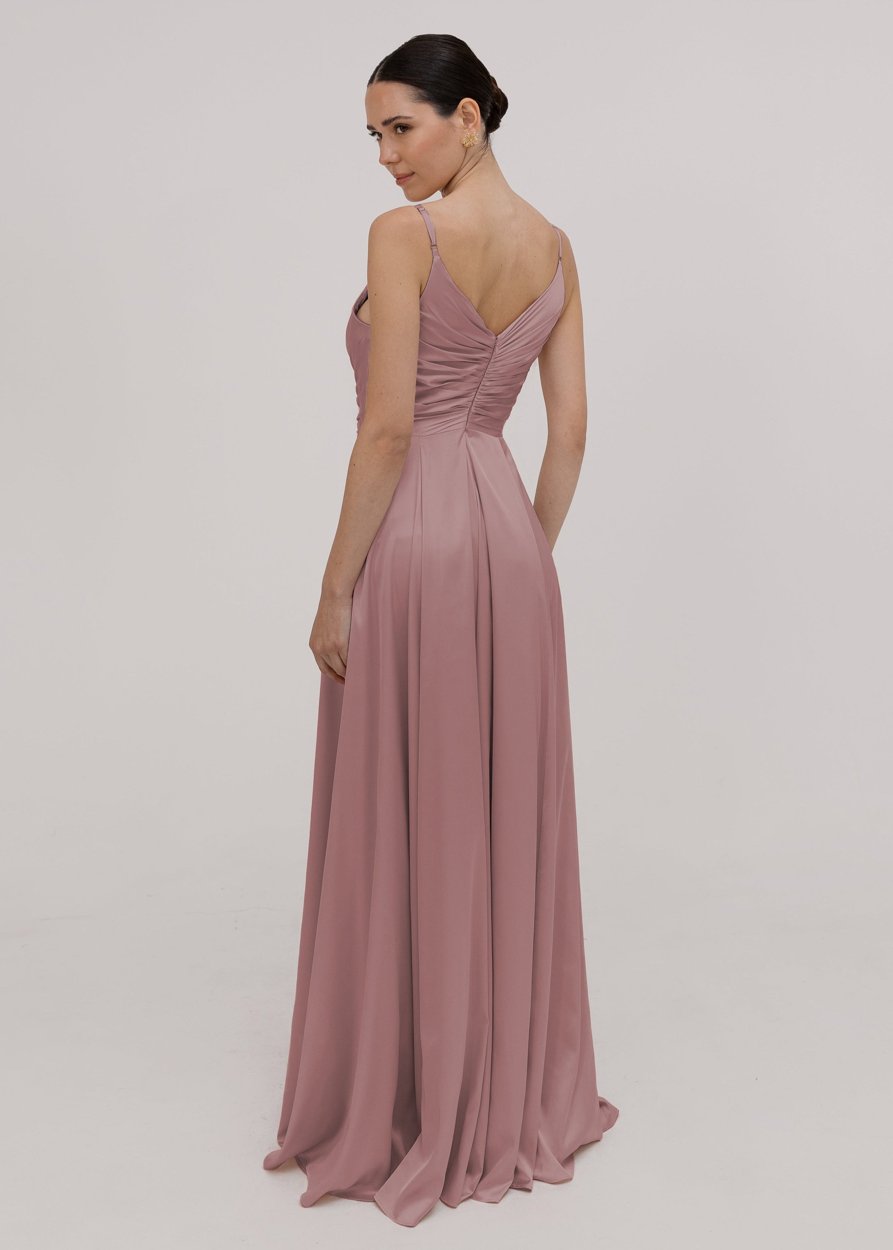 Model wearing a floor length pink satin bridesmaid dress with V back and spaghetti straps back view by TH&TH Bridesmaids.