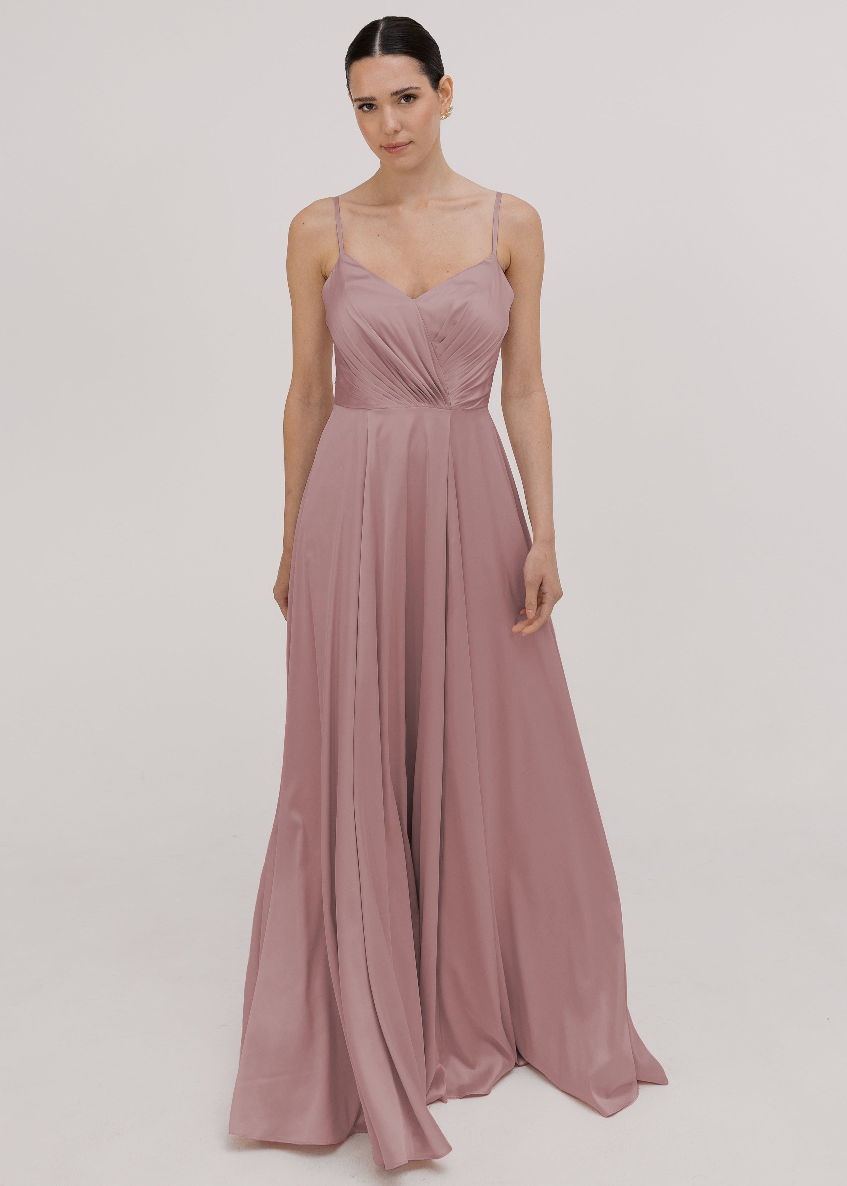 Model wearing a floor length pink satin bridesmaid dress with V back and spaghetti straps by TH&TH Bridesmaids.