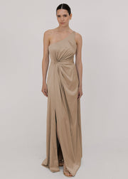 Model wearing a floor length champagne satin bridesmaid dress with one shoulder and slit in skirt by TH&TH Bridesmaids.
