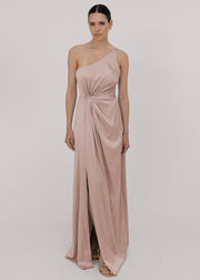 Model wearing a floor length blush pink satin bridesmaid dress with one shoulder and slit in skirt by TH&TH Bridesmaids.