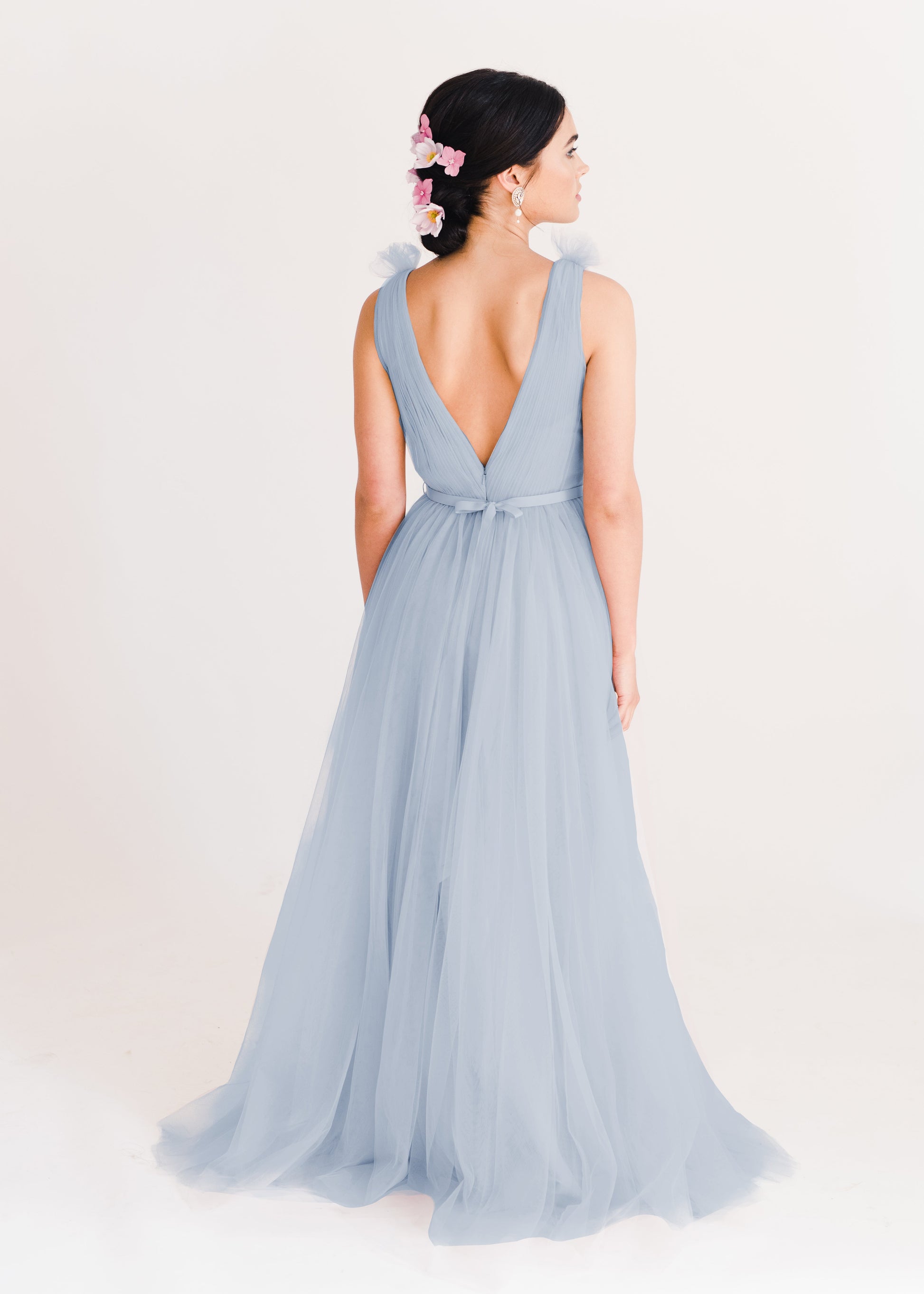 A dusty blue bridesmaid dress with mock wrap front, pleated bodice, on a white background by TH&TH Bridesmaids. 
