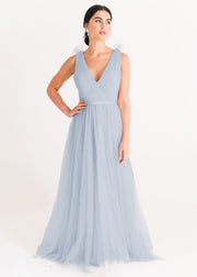 A dusty blue bridesmaid dress with mock wrap front, pleated bodice, on a white background by TH&TH Bridesmaids. 
