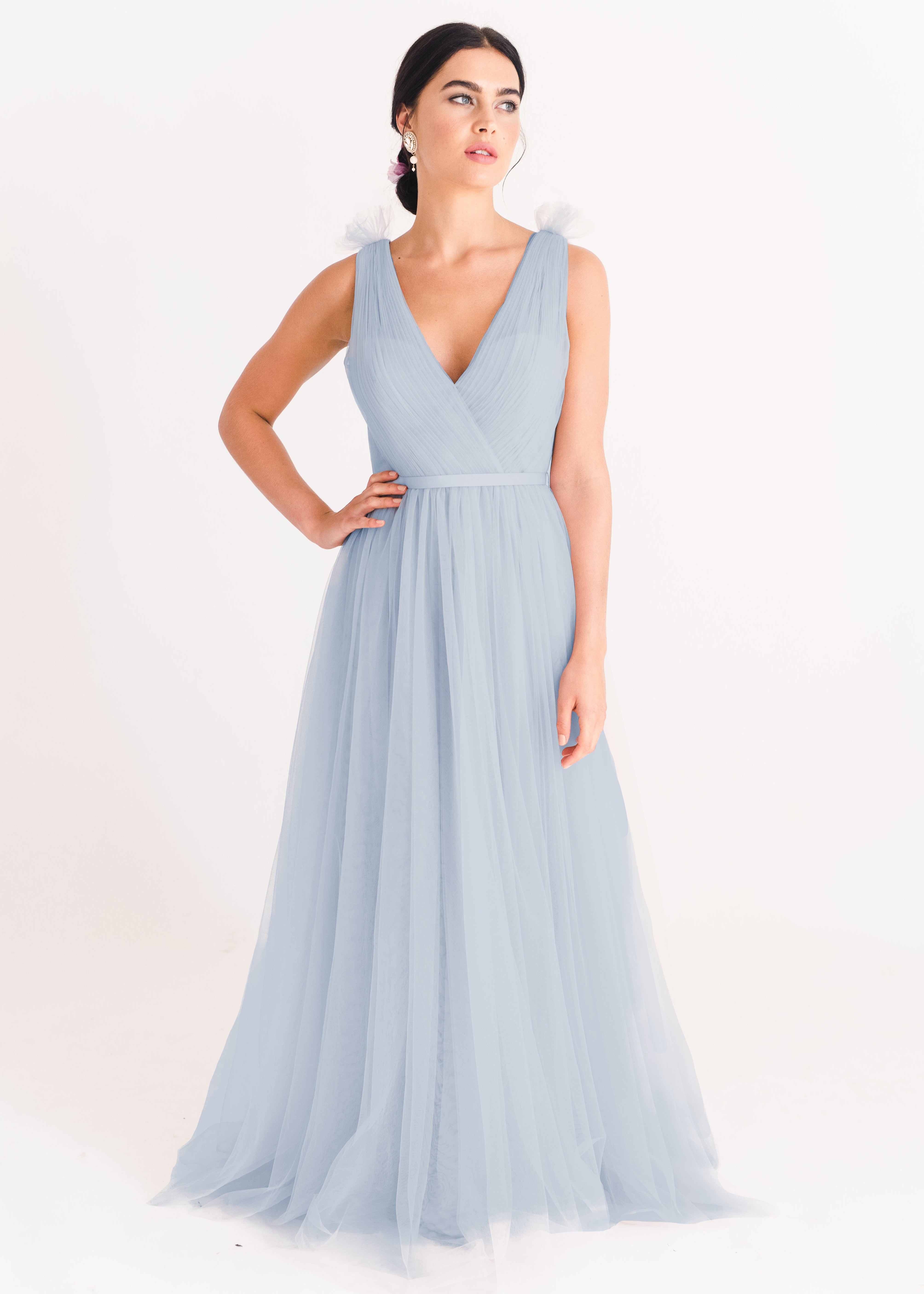 A dusty blue bridesmaid dress with mock wrap front, pleated bodice, on a white background by TH&TH Bridesmaids. 