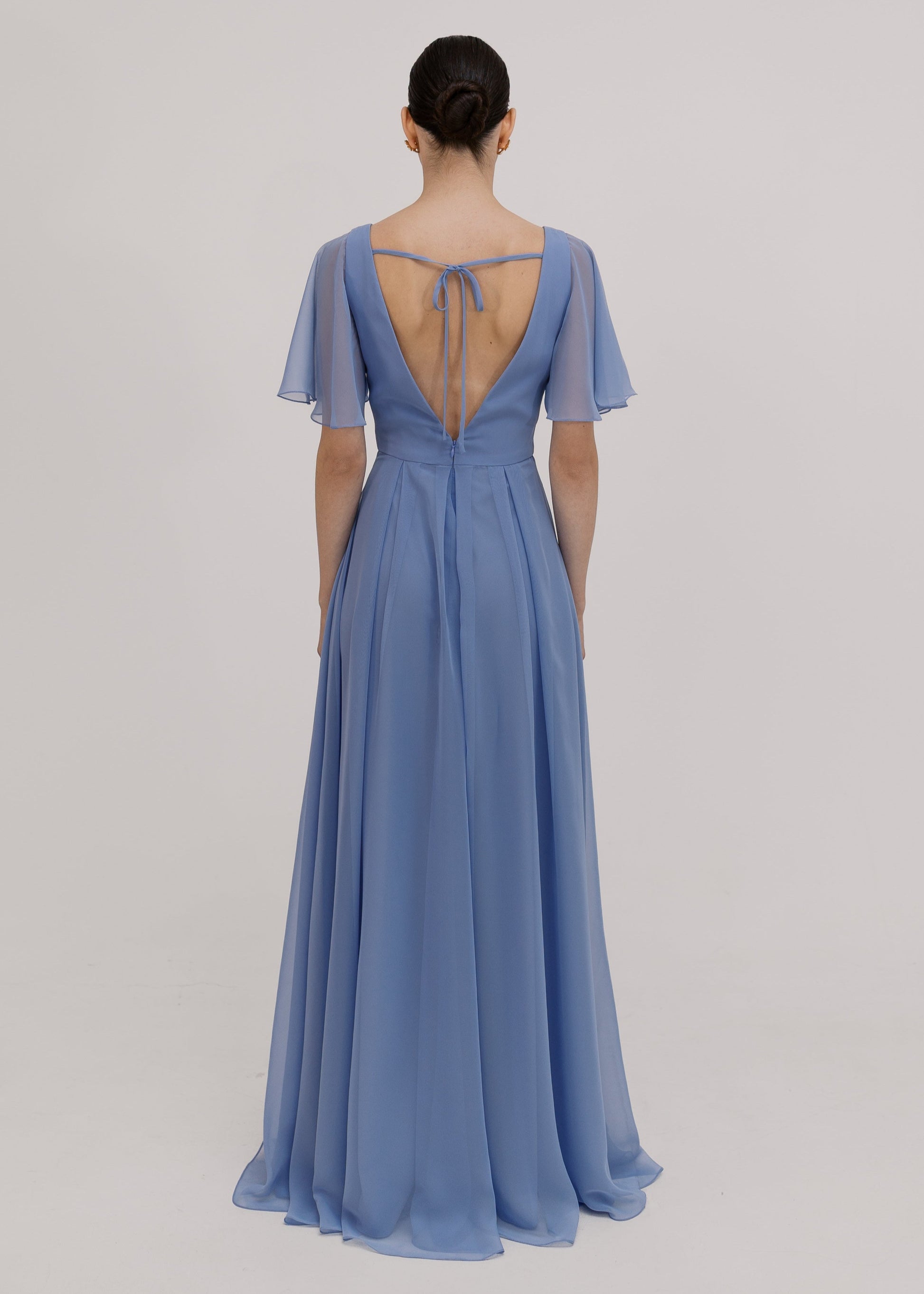 Woman wearing a long blue dress with short sleeves, V neck and a line skirt in french blue chiffon.