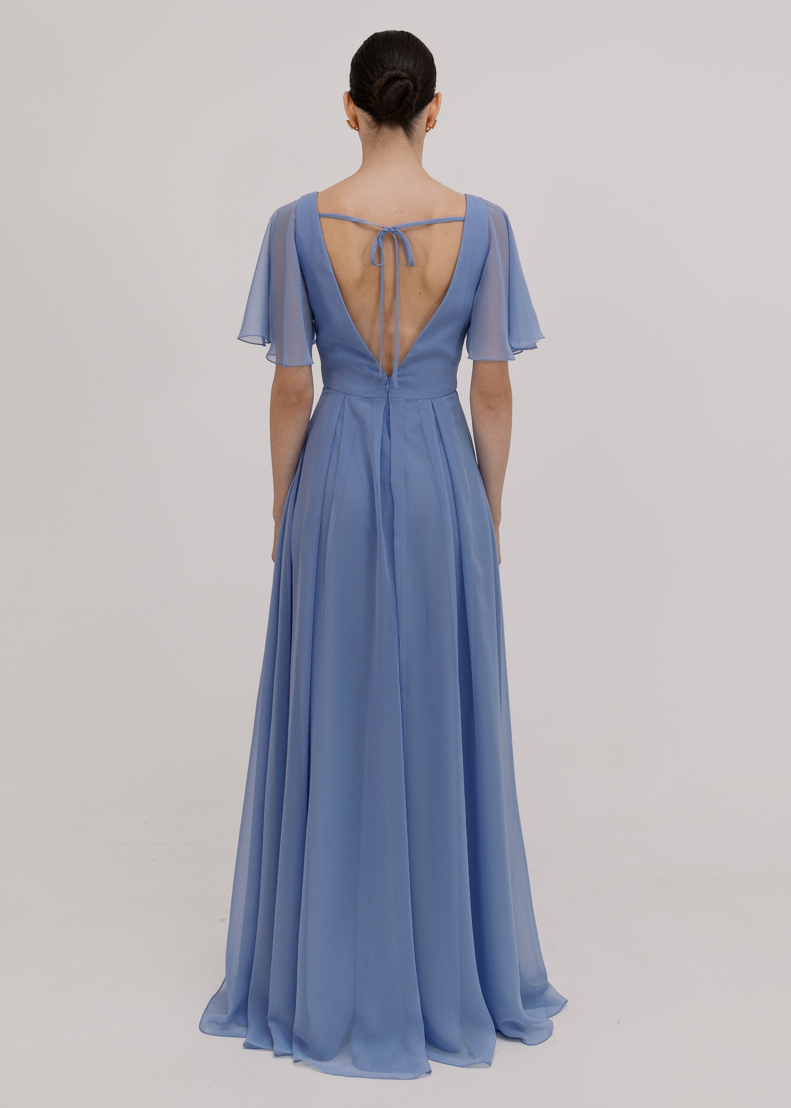 Woman wearing a long blue dress with short sleeves, V neck and a line skirt in french blue chiffon.