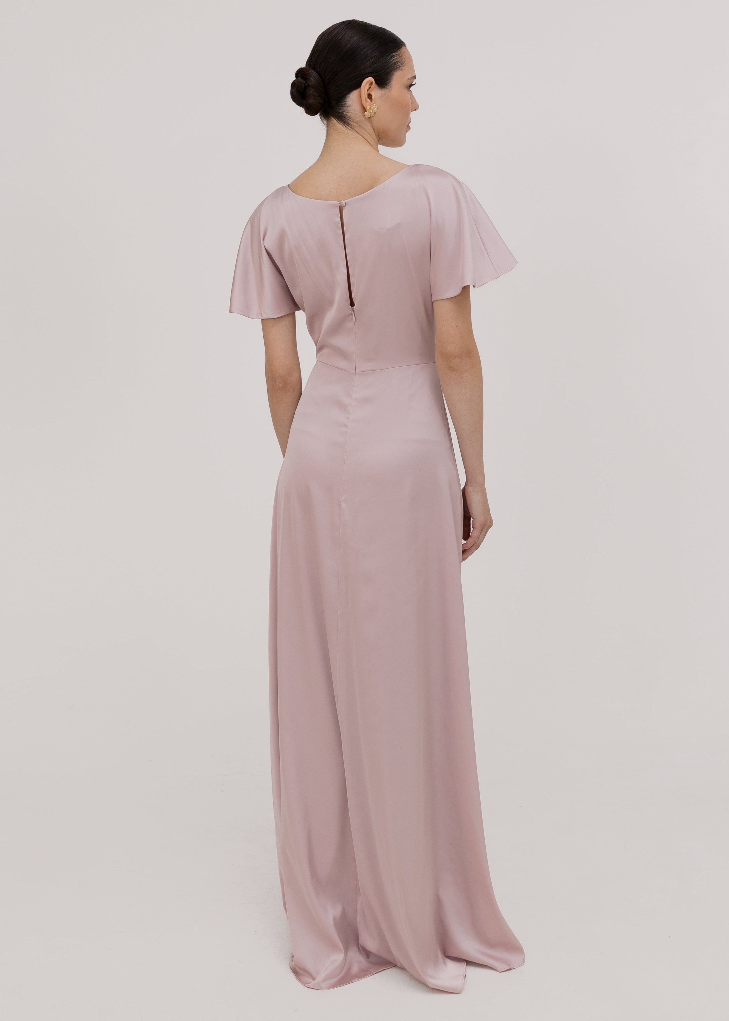 Woman wearing a long smoked blush pink bridesmaid dress with sleeves, bra friendly high back and twist knot detail in satin.