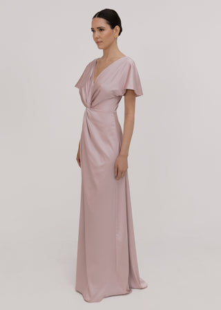 Woman wearing a long smoked blush pink bridesmaid dress with sleeves, bra friendly high back and twist knot detail in satin.